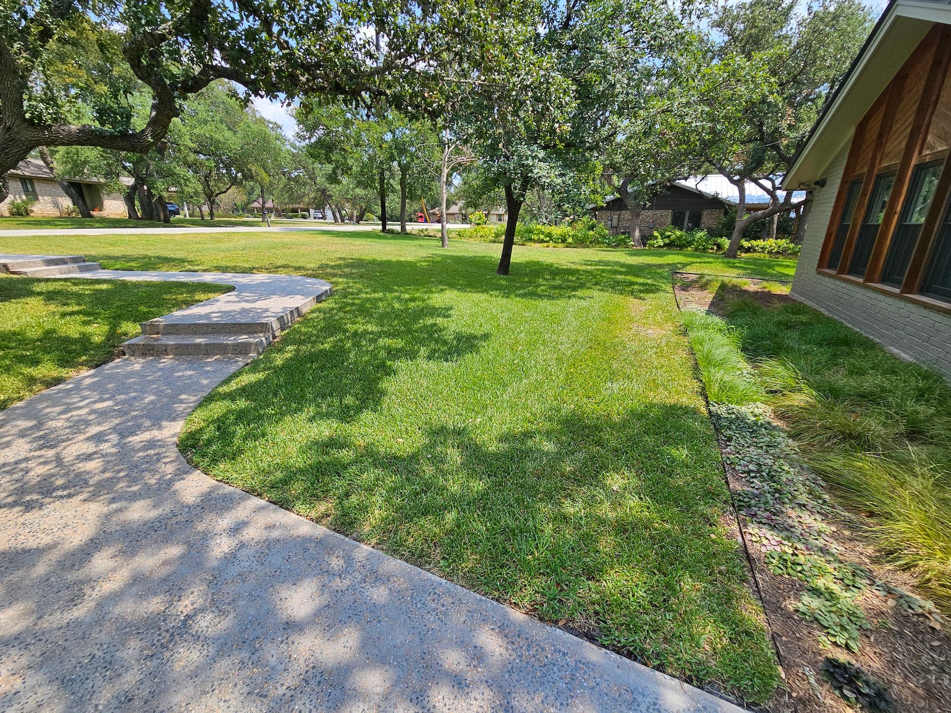 A house with a lush green lawn and a walkway leading to it.