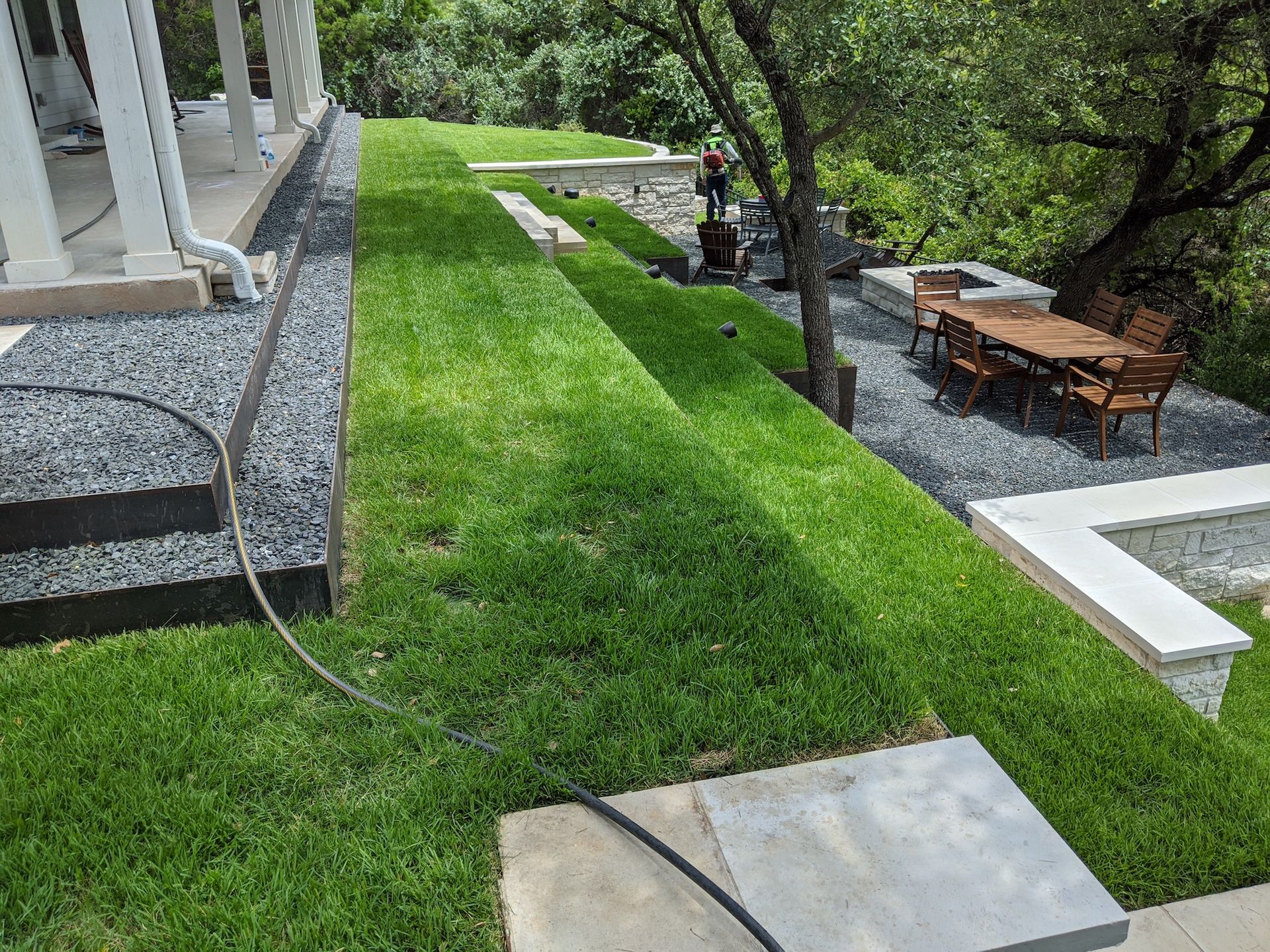 A lush green lawn with a table and chairs in the background.