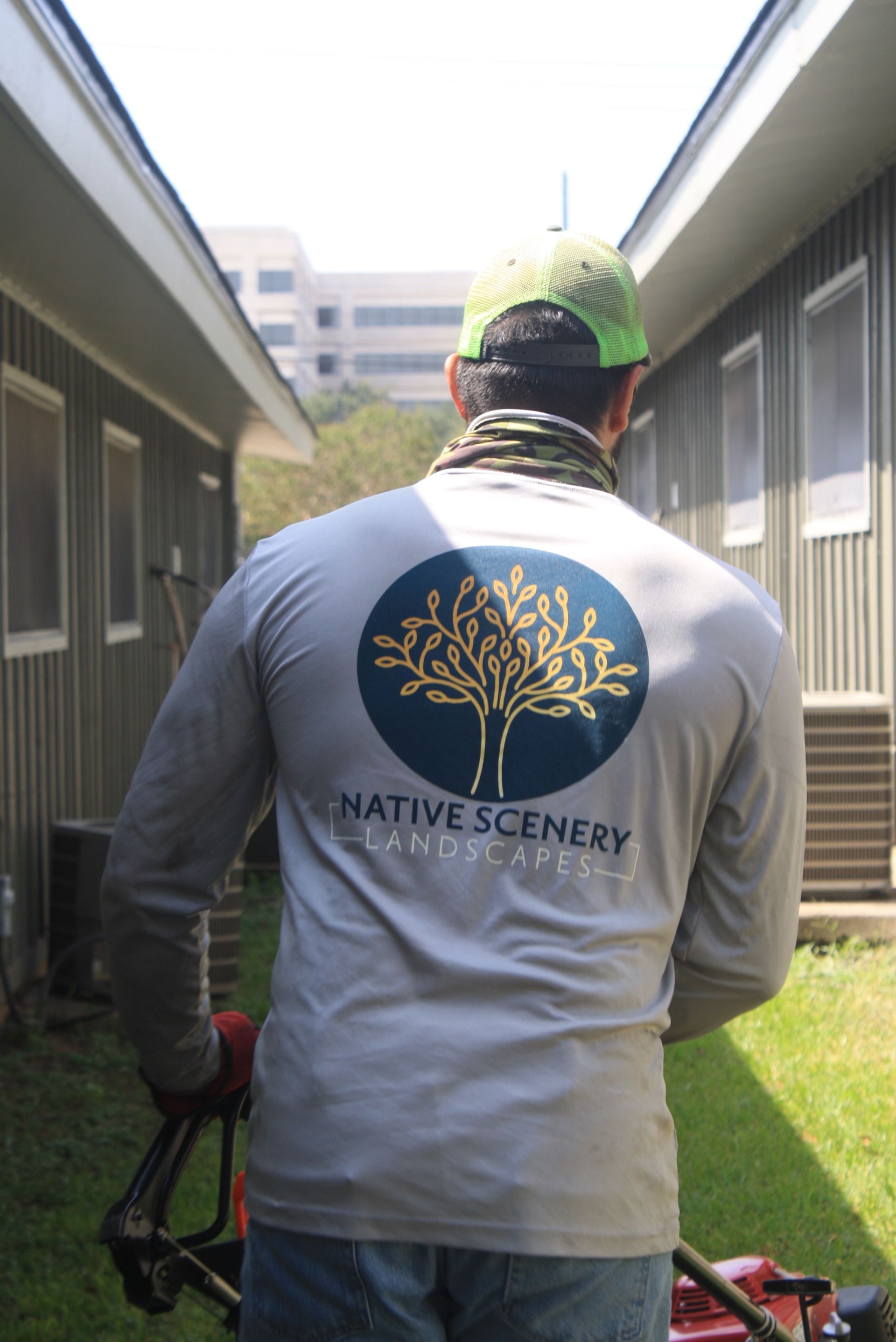 A man wearing a native scenery shirt is mowing the grass