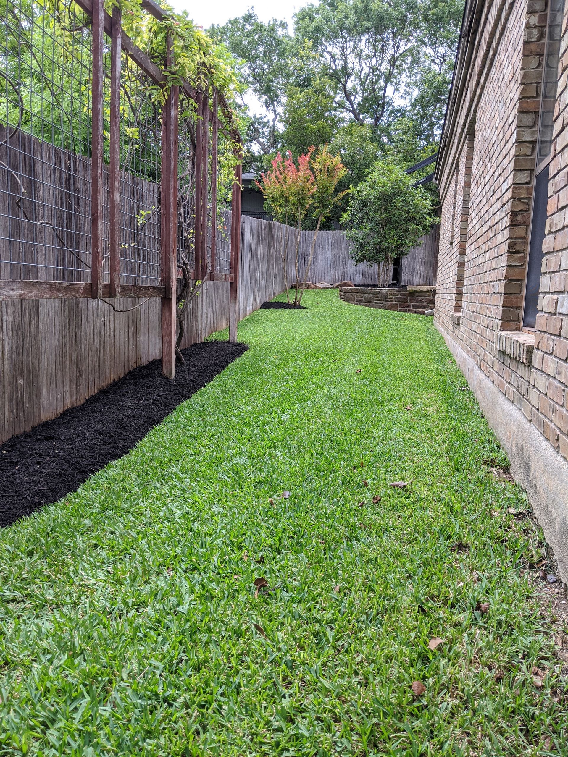 A lush green lawn next to a brick building.
