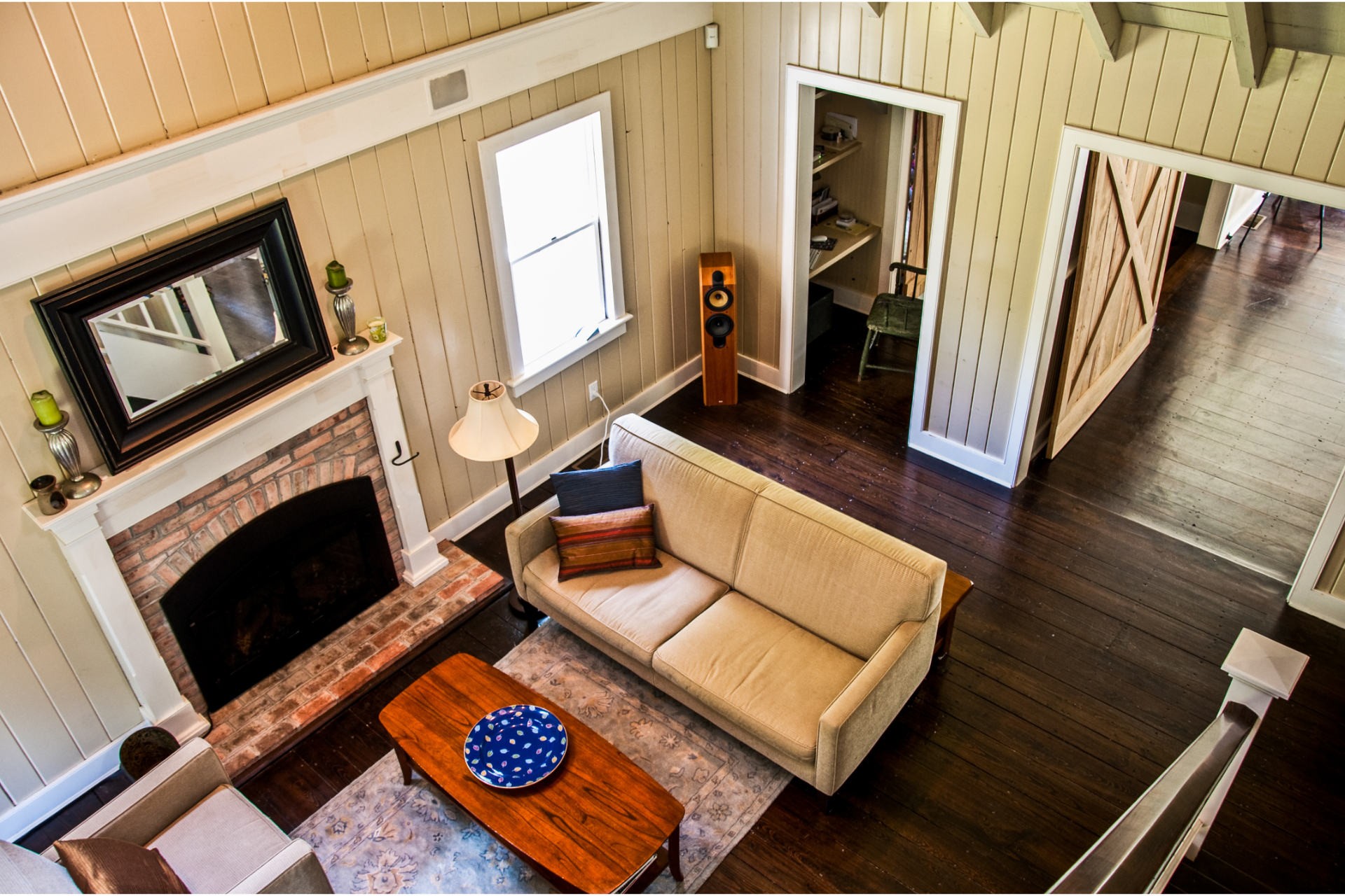 Overhead view of a living room with a couch, fireplace, and dark wood floors.