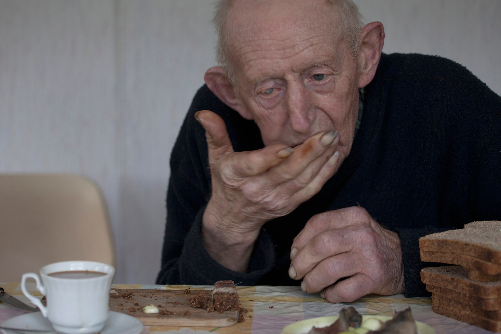Een oudere man eet  een haring op zijn brood