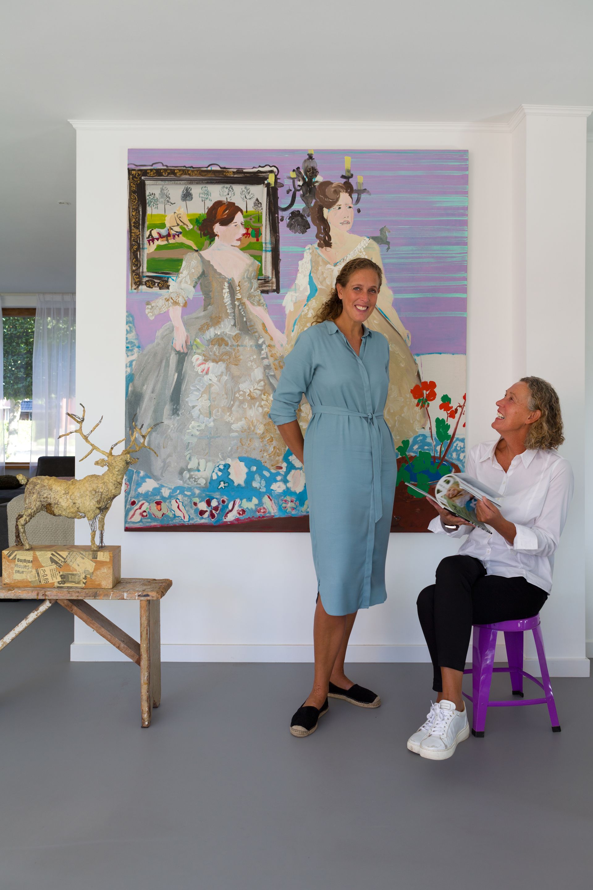 Twee vrouwen poseren voor een groot schilderij. Foto Elise Klinkert