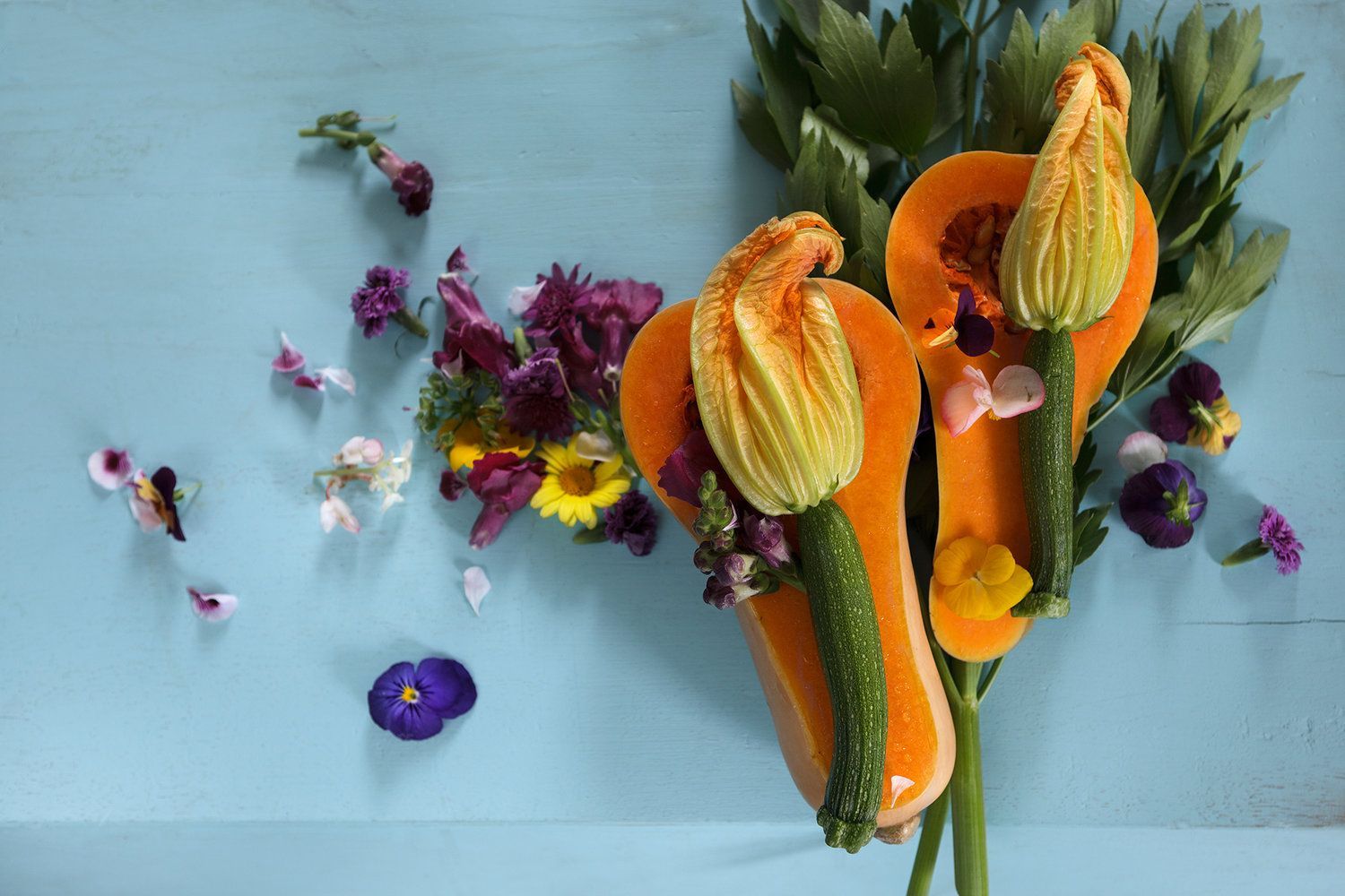 Gesneden pompoen, versierd met bloemen, tegen een blauwe achtergrond.