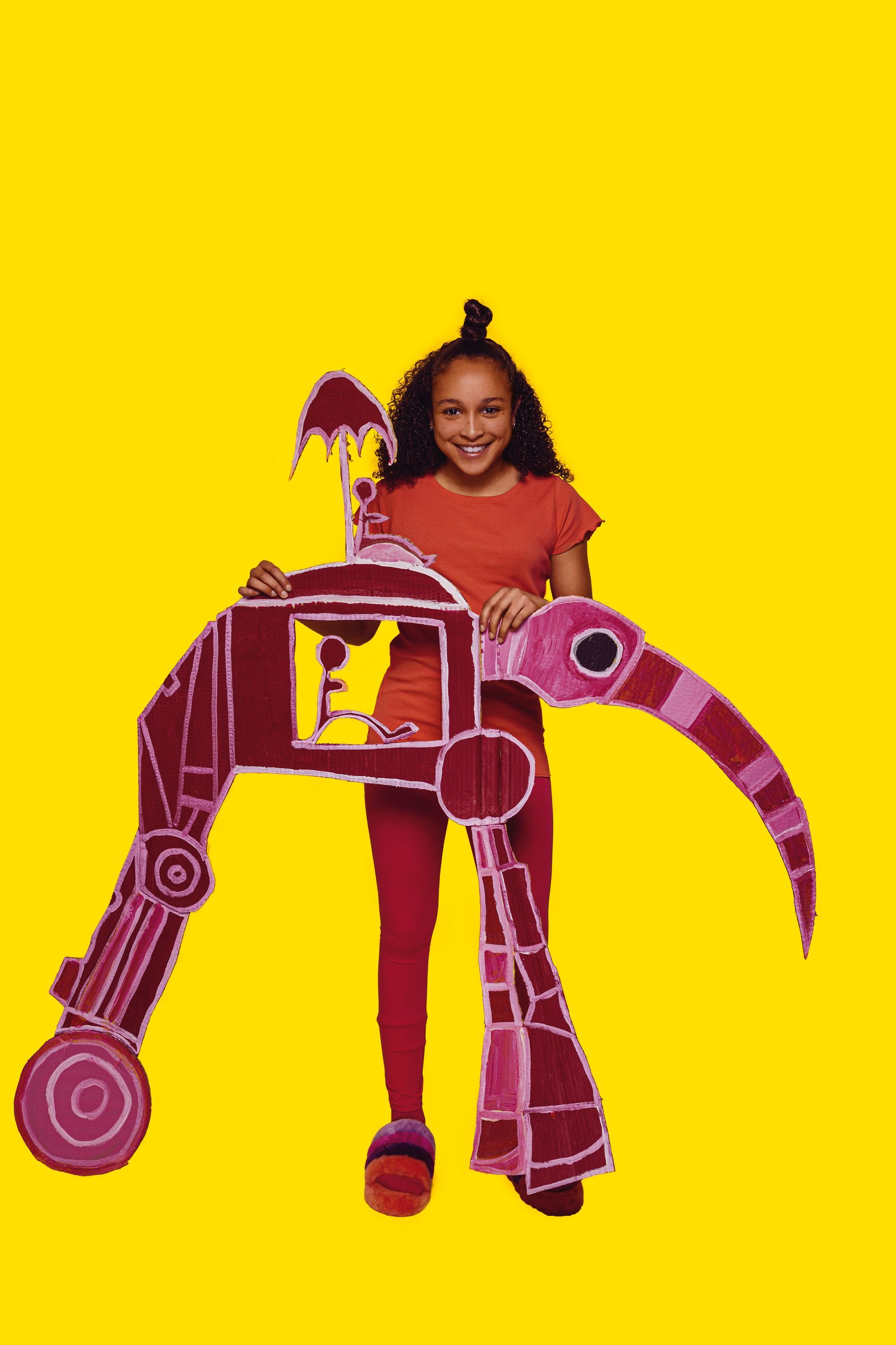 Meisje houdt een kartonnen figuur vast van een eigenaardig wezen met een lange snavel, op geel.