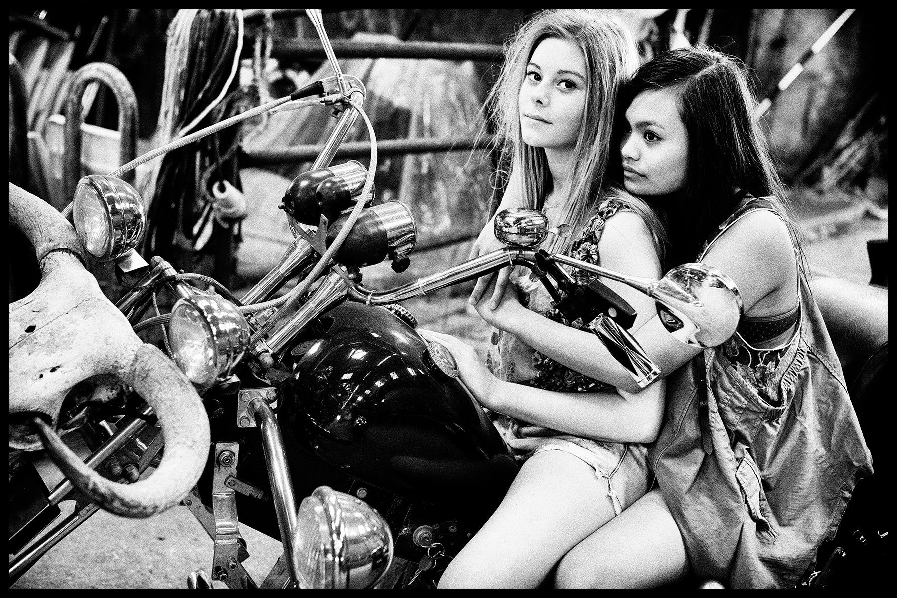 Twee vrouwen zitten op een motorfiets in een garage. Zwart-wit, poserend .Foto Elise Klinkert