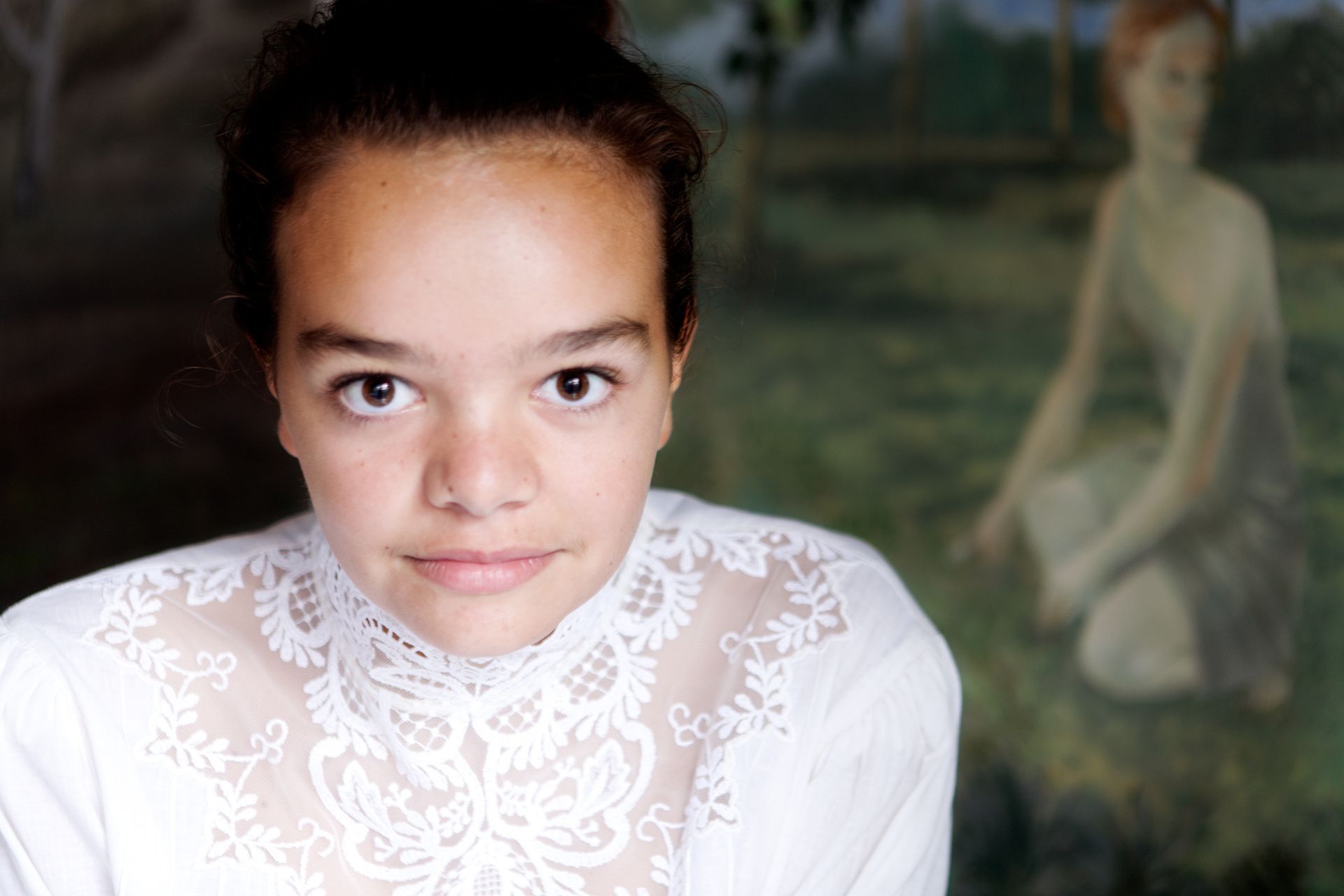 Jonge vrouw met donker haar in een wit kanten topje, schilderij op de achtergrond.Foto Elise Klinkert