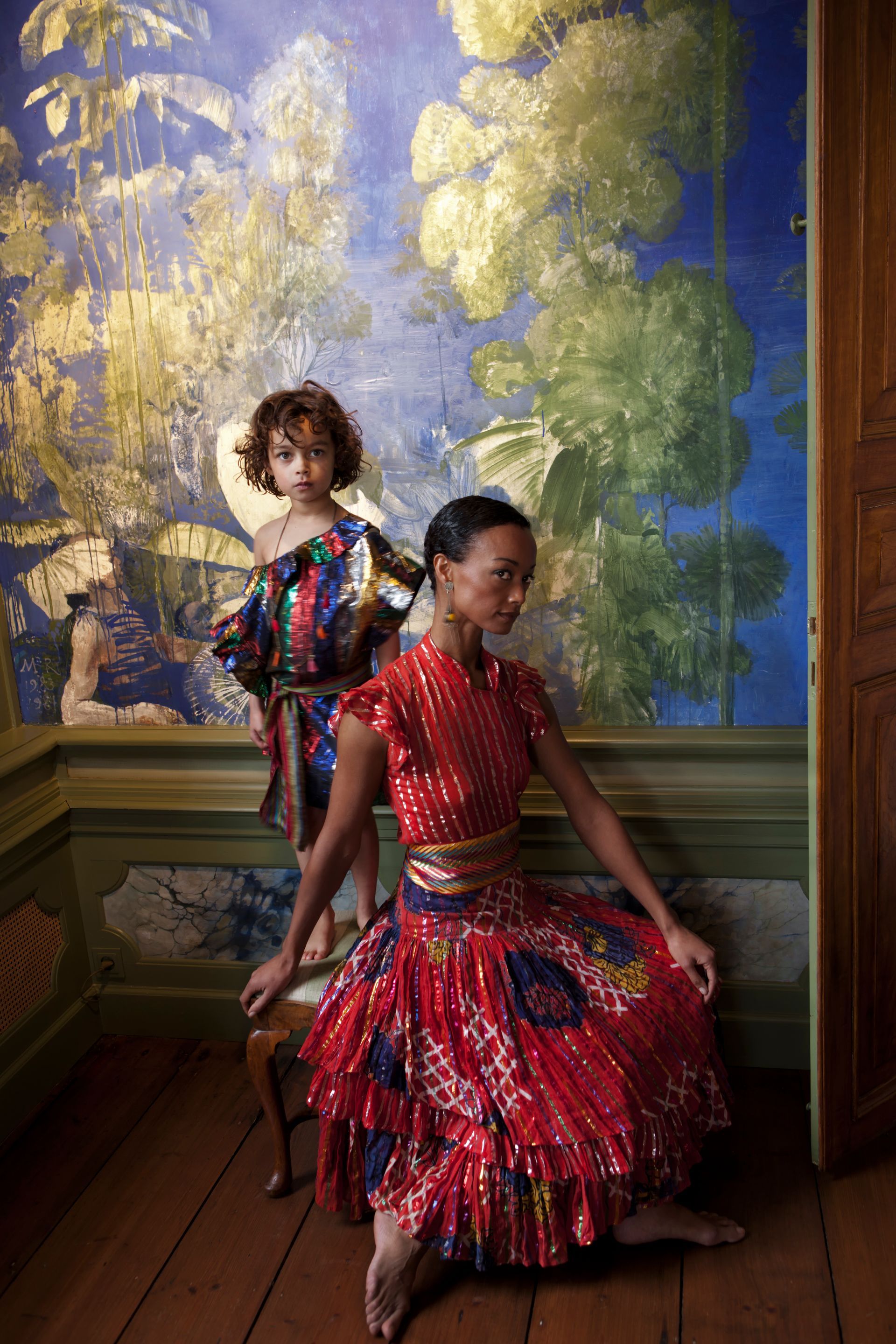 Vrouw en kind in kleurrijke jurken met patronen poseren binnenshuis in een elegante omgeving .Foto Elise Klinkert