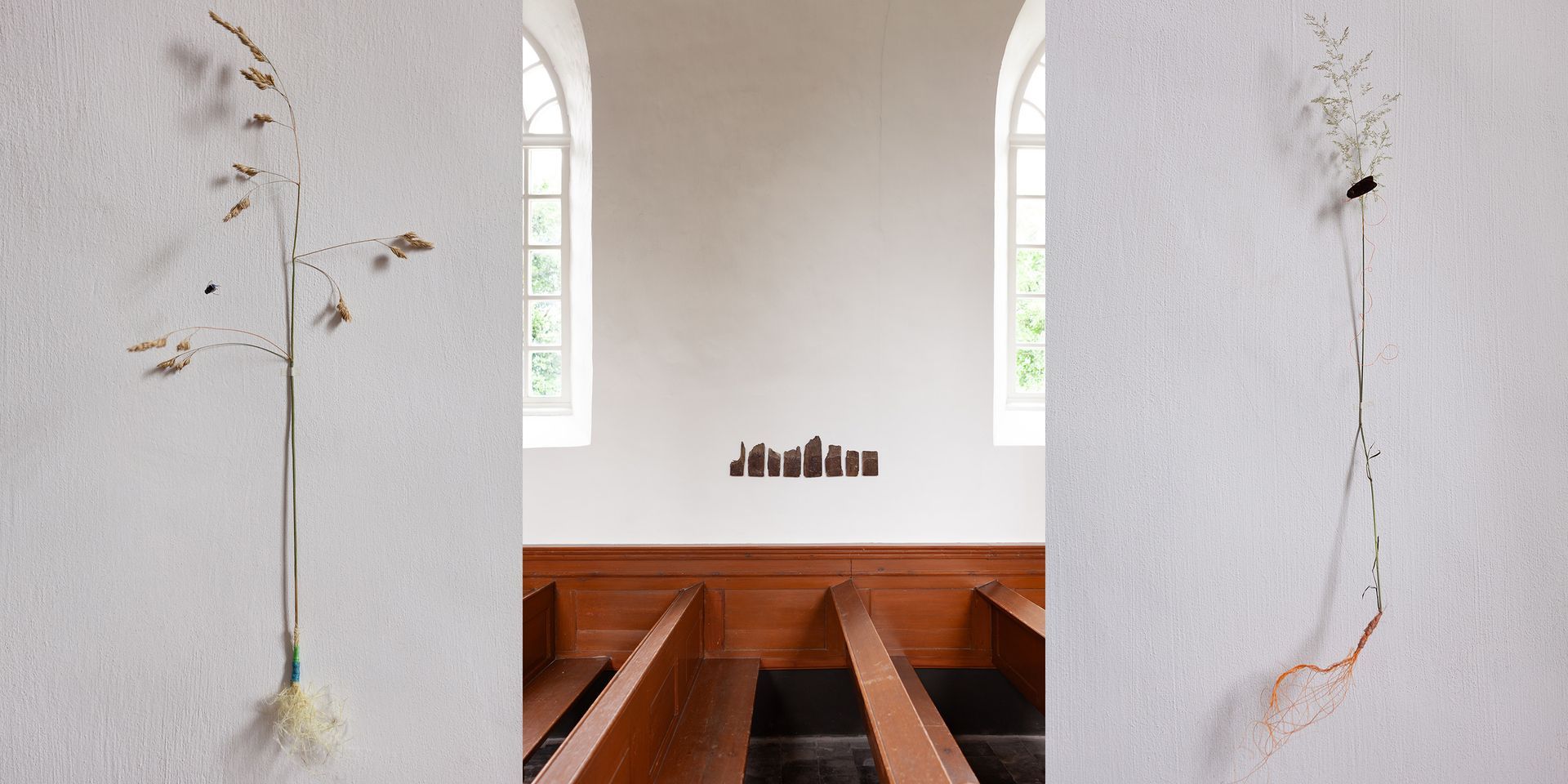 Minimalistisch wit kerkinterieur met houten kerkbanken, hoge ramen en hangende gedroogde bloemen.