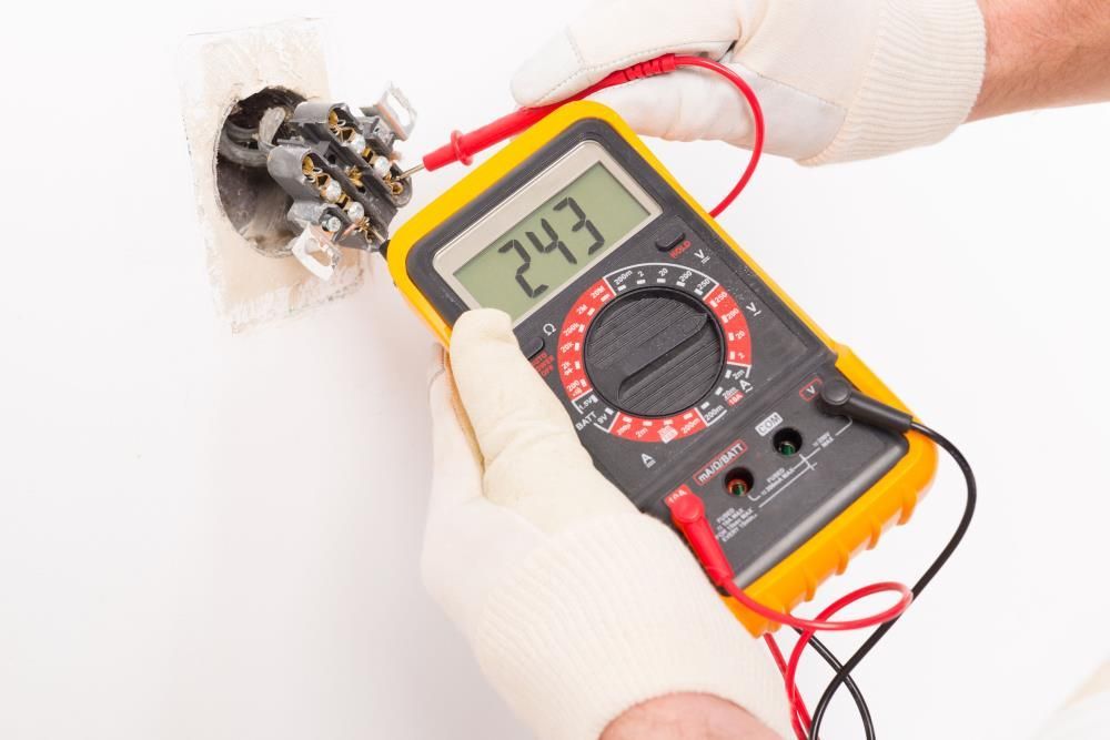 Hands in gloves testing electrical outlet with a multimeter, displaying 243 volts.