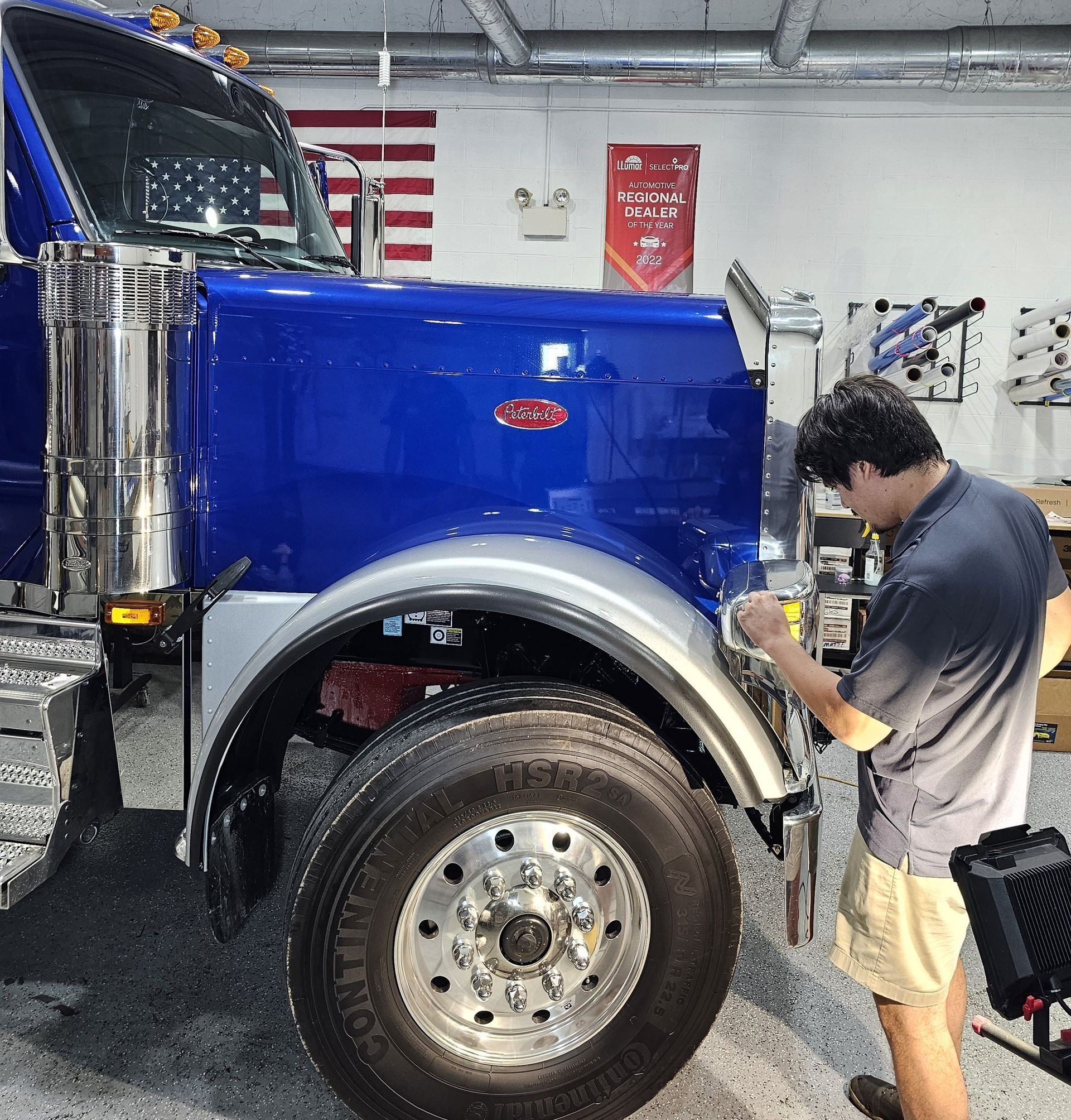 A man is working on a blue truck in a garage