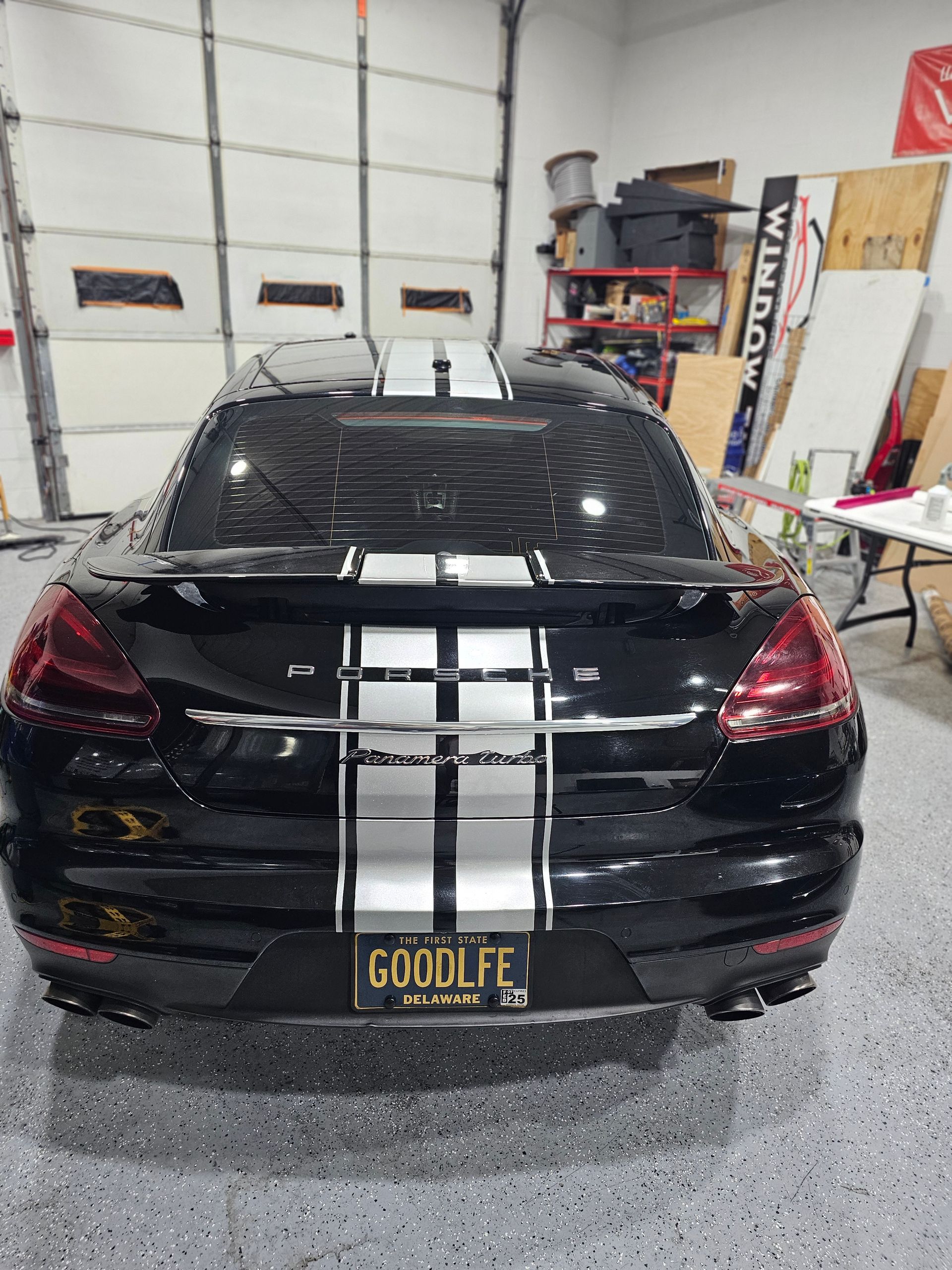 A man is working on the hood of a car in a garage.