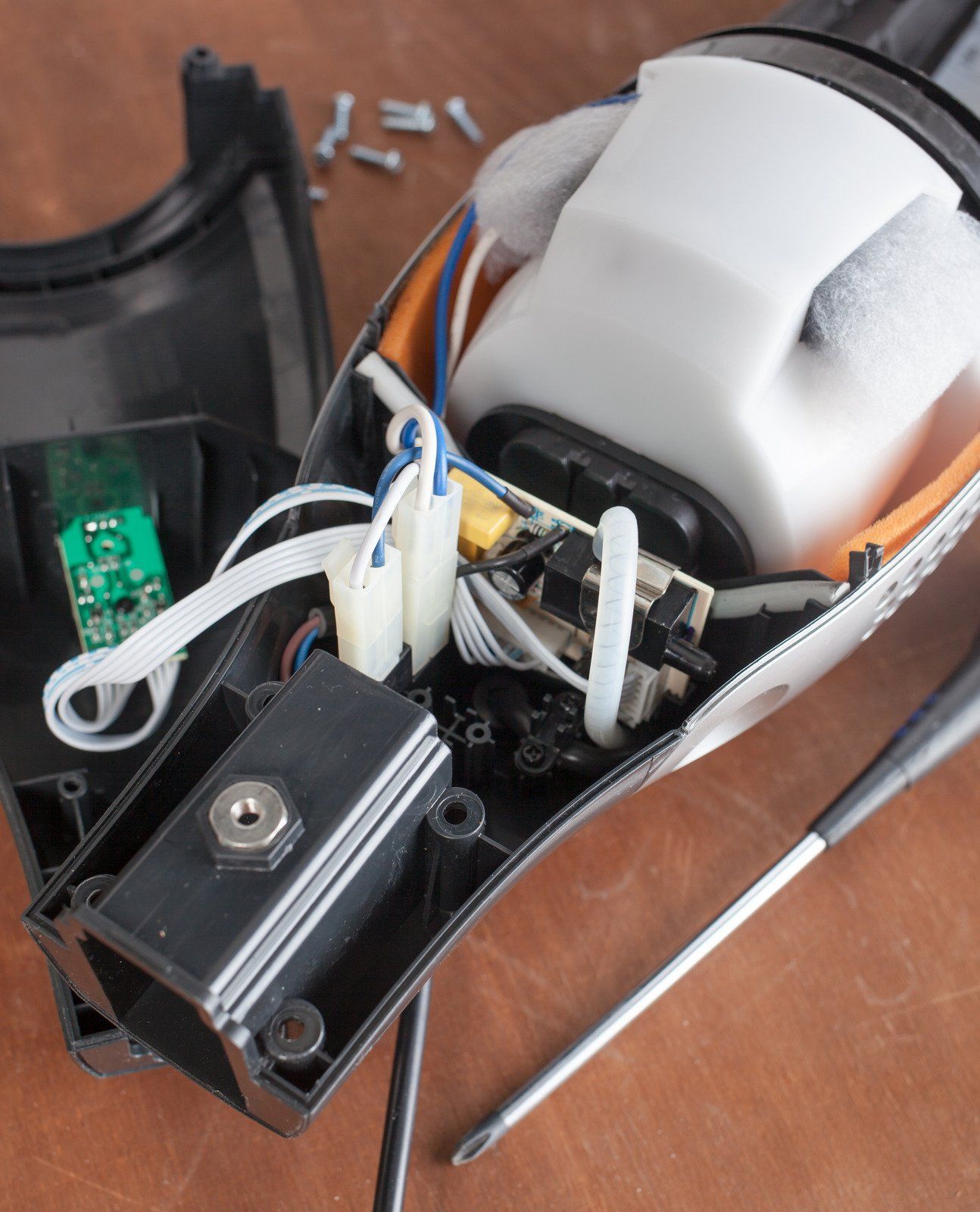 Disassembled black and white hand sanitizer dispenser, revealing internal components and circuit board.