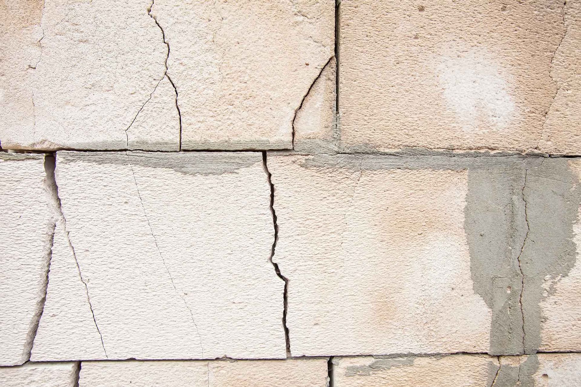 Cracked concrete blocks on a basement wall showing visible damage that needs repair. Cracked concrete blocks on a basement wall showing visible damage that needs repair.