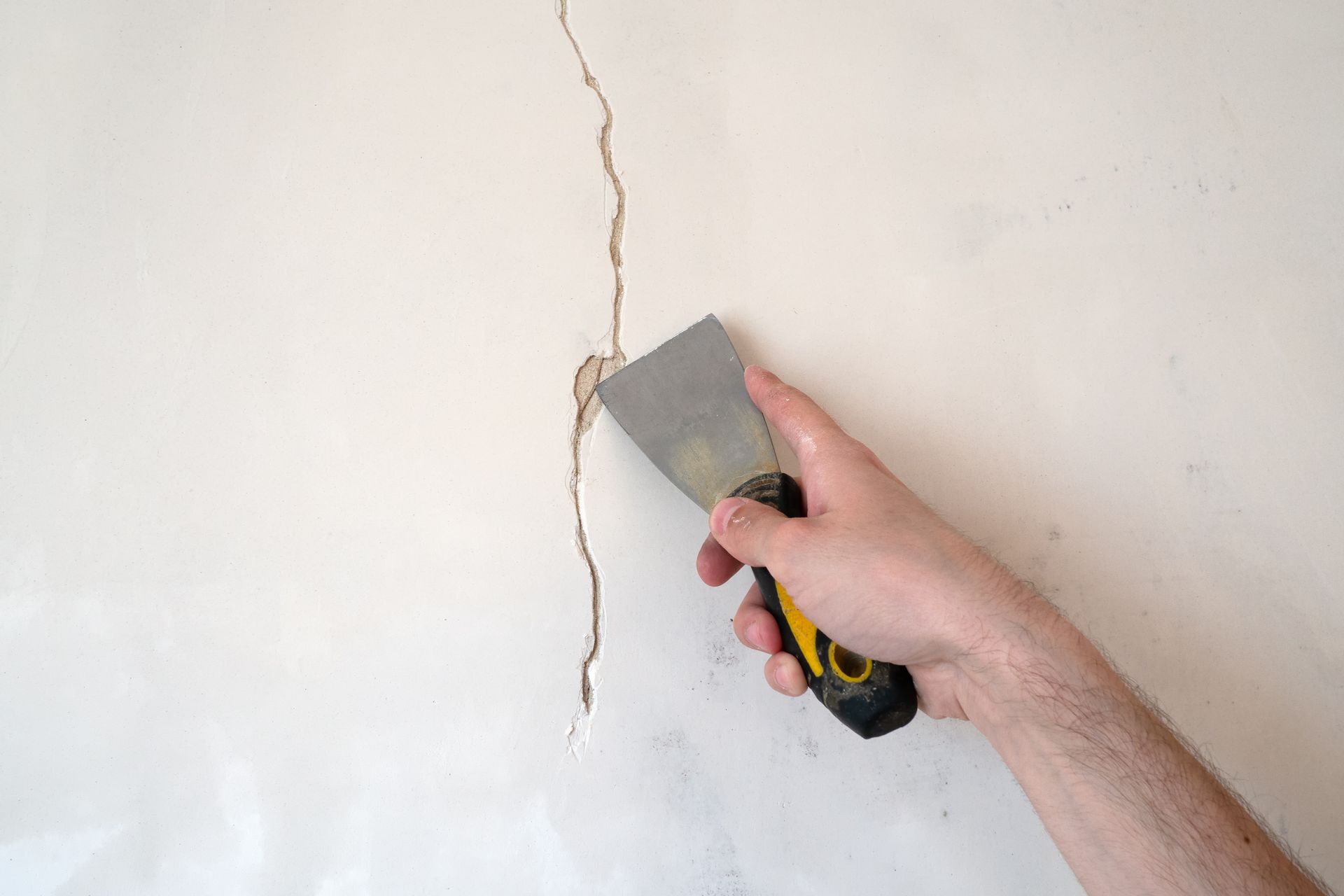 Repairing a wall crack with a putty knife before patching and painting Repairing a wall crack with a putty knife before patching and painting