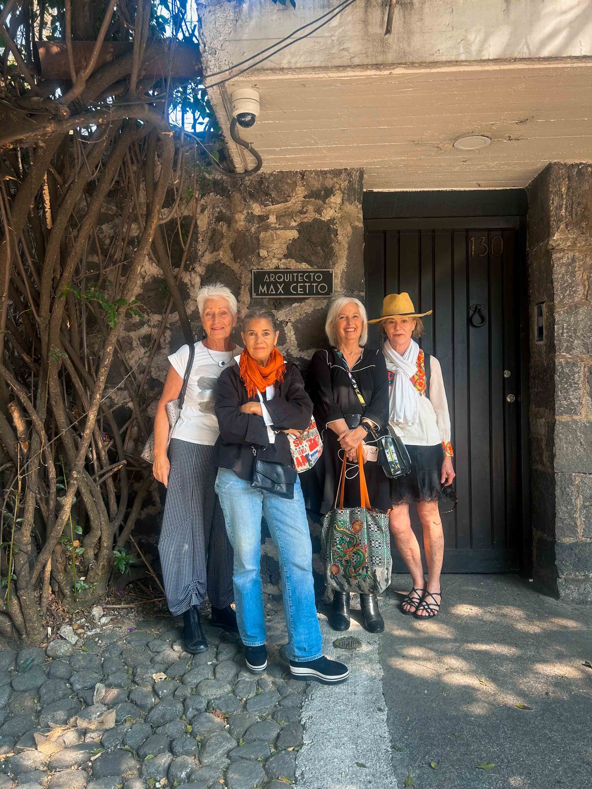 A group of women are posing for a picture in front of a stone building.