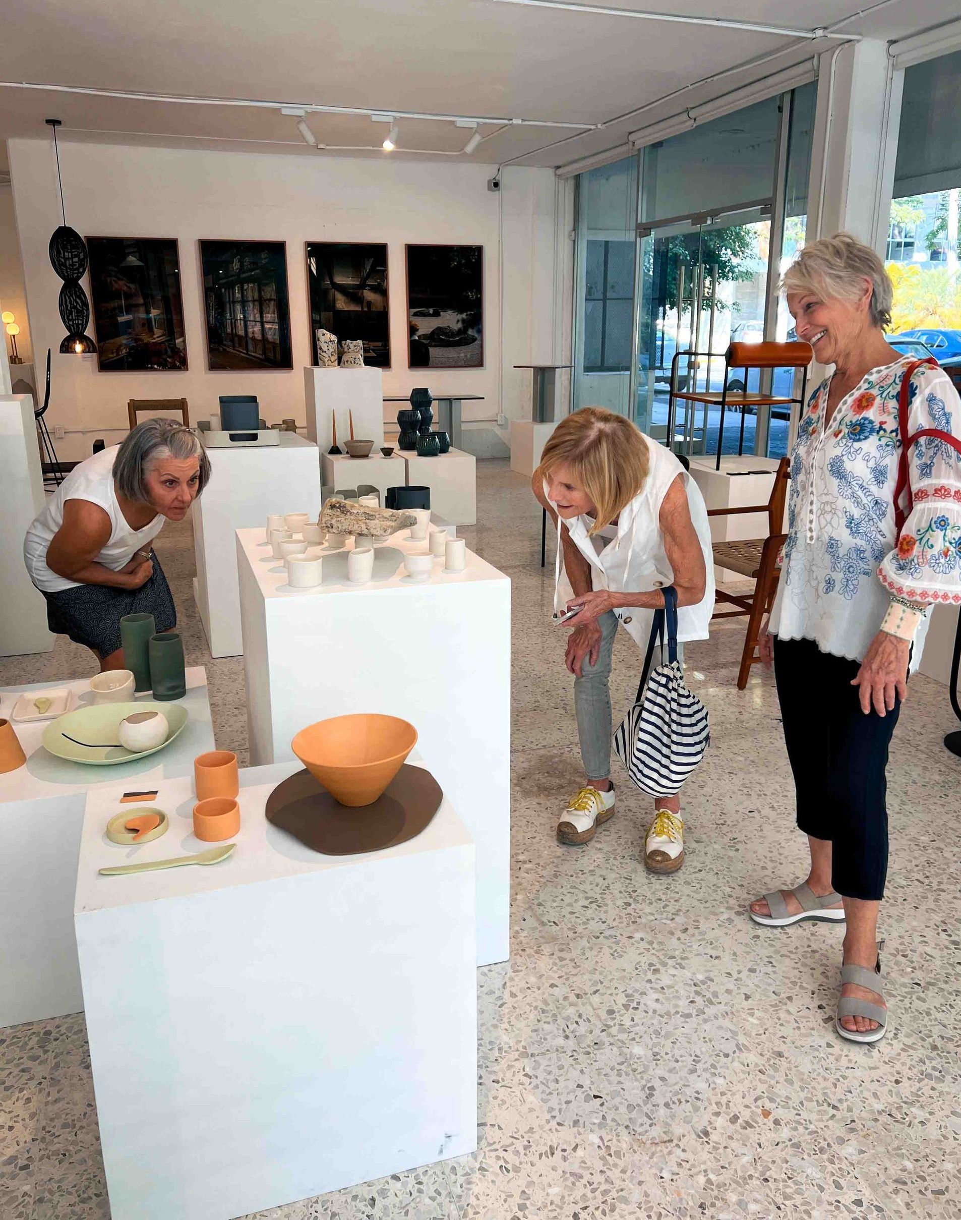 Three women are looking at a display of ceramics in a museum.