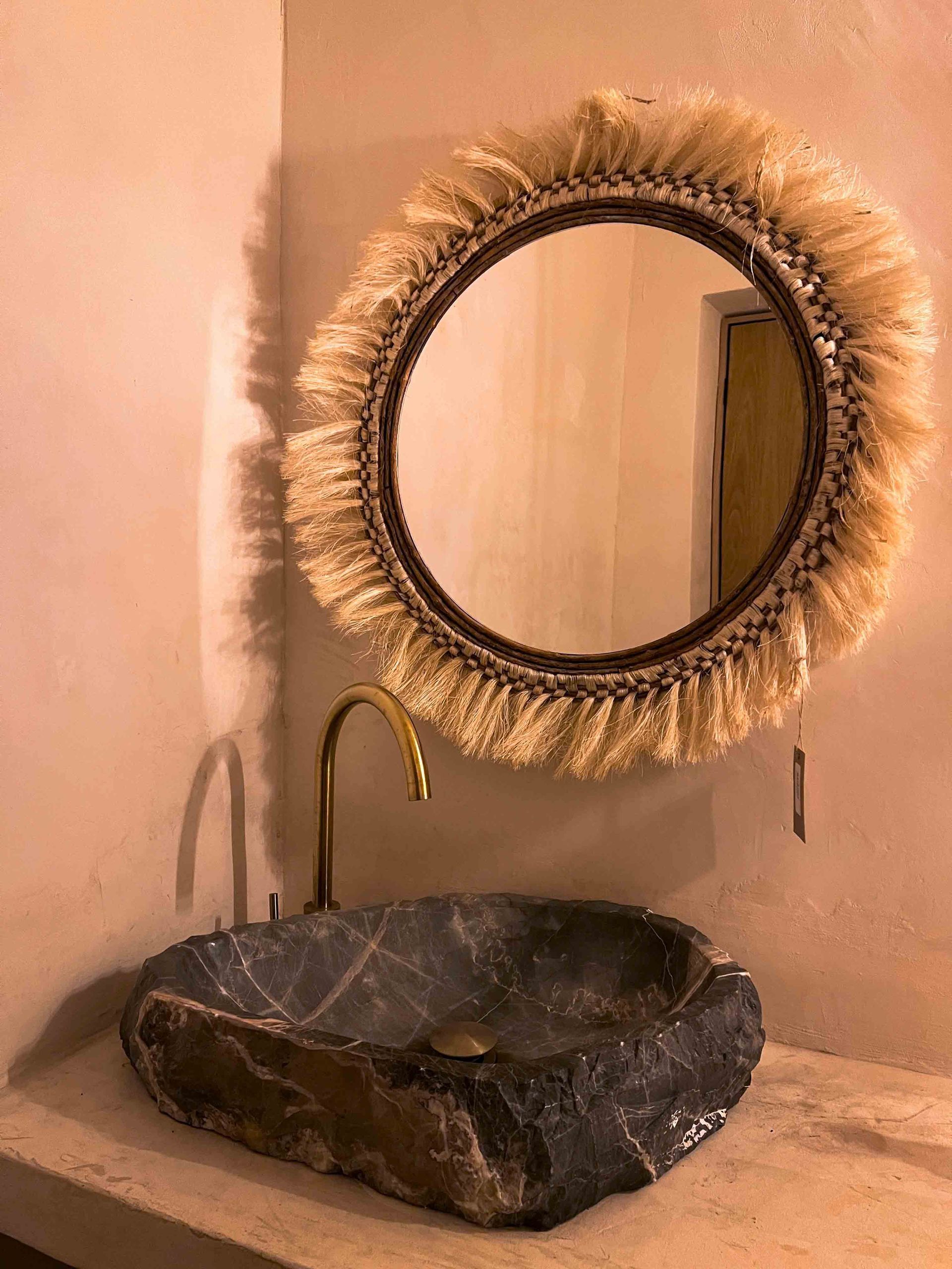 A bathroom sink with a round mirror above it.
