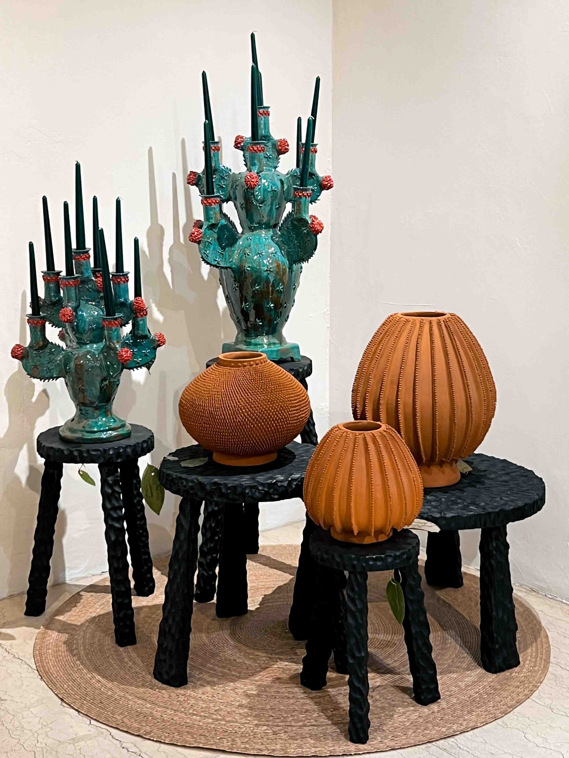 A group of vases are sitting on stools in a room.