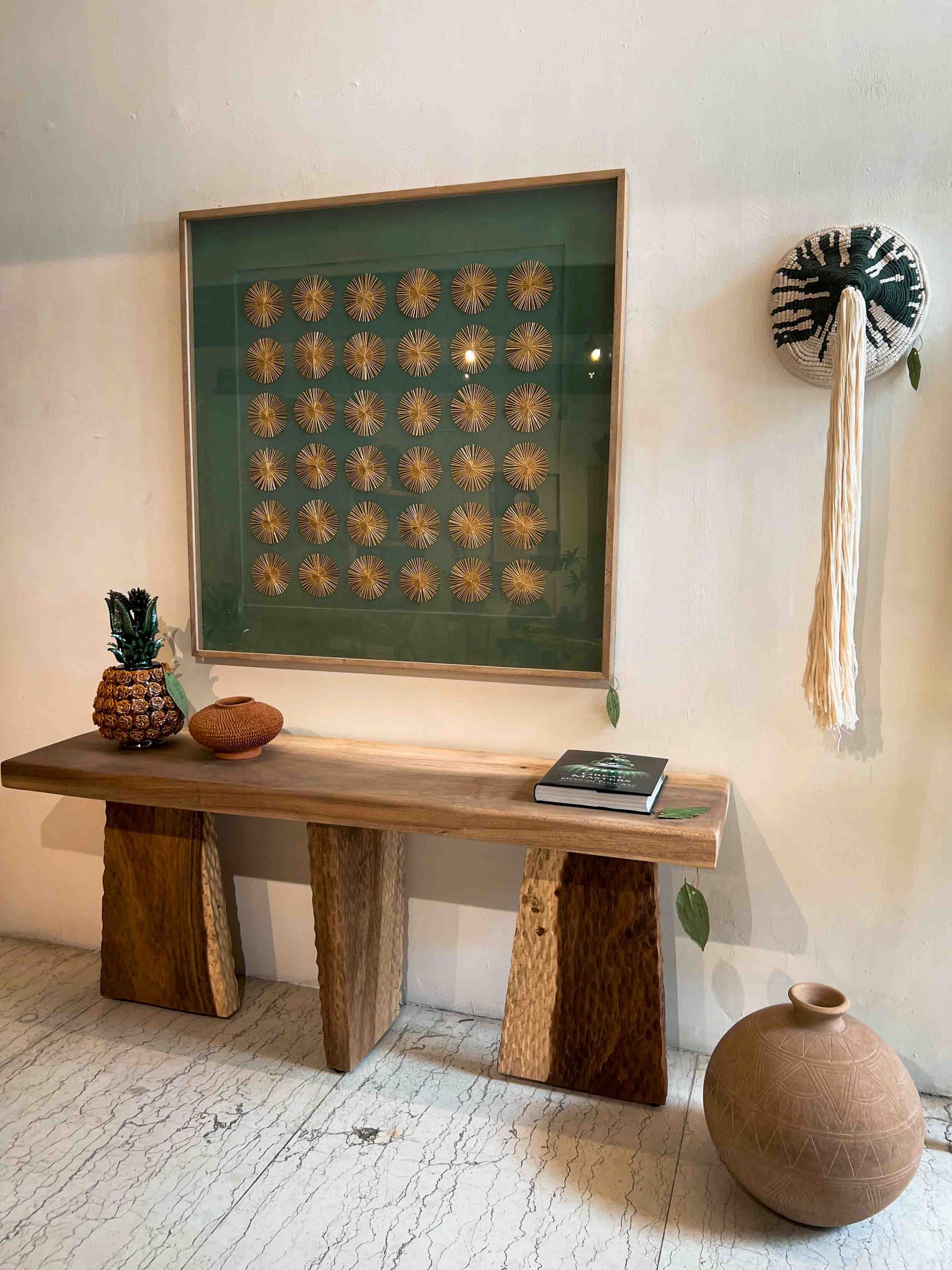 A wooden bench is sitting in front of a wall with a picture on it.