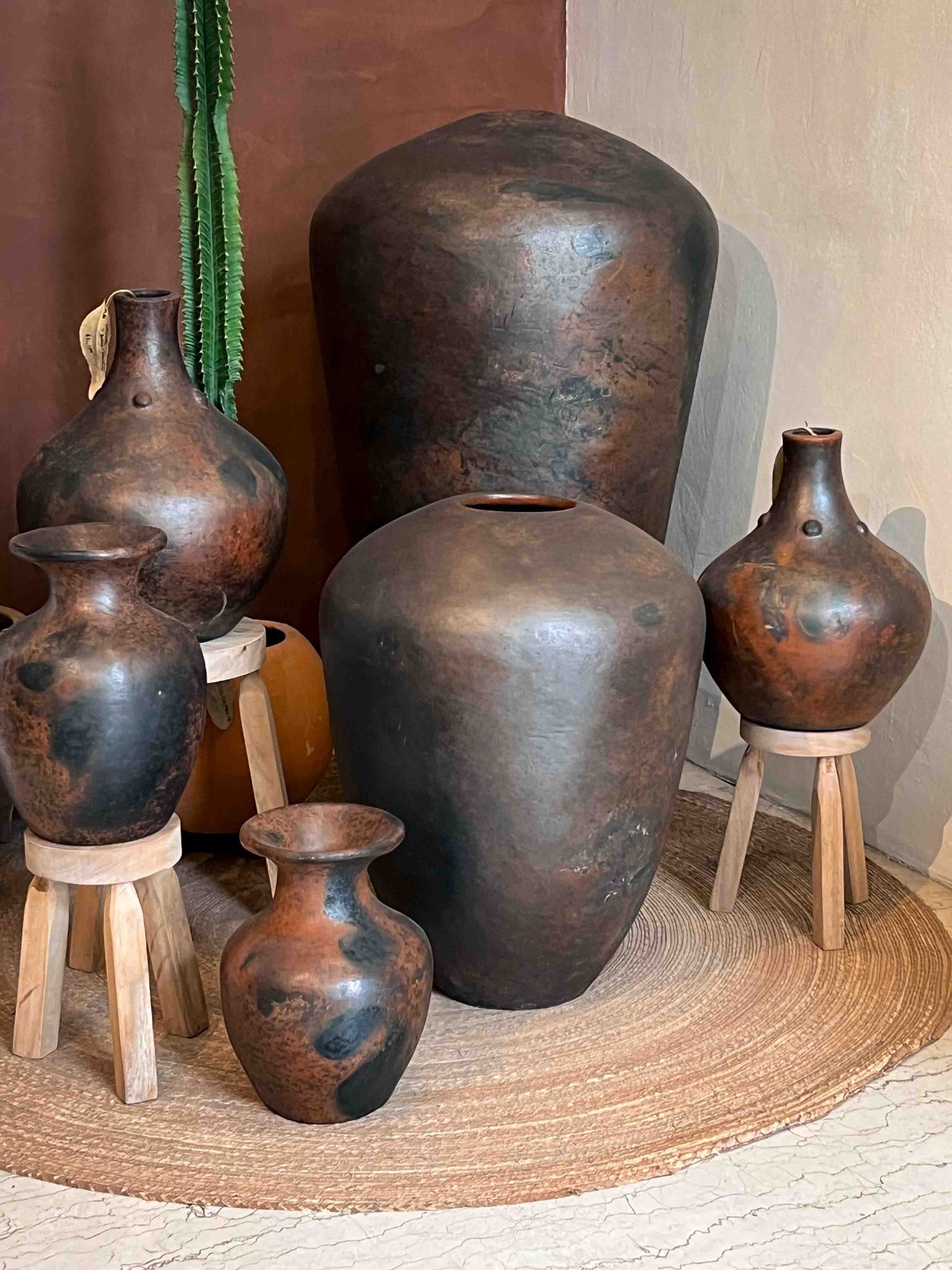 A group of vases sitting on wooden stools in a room.