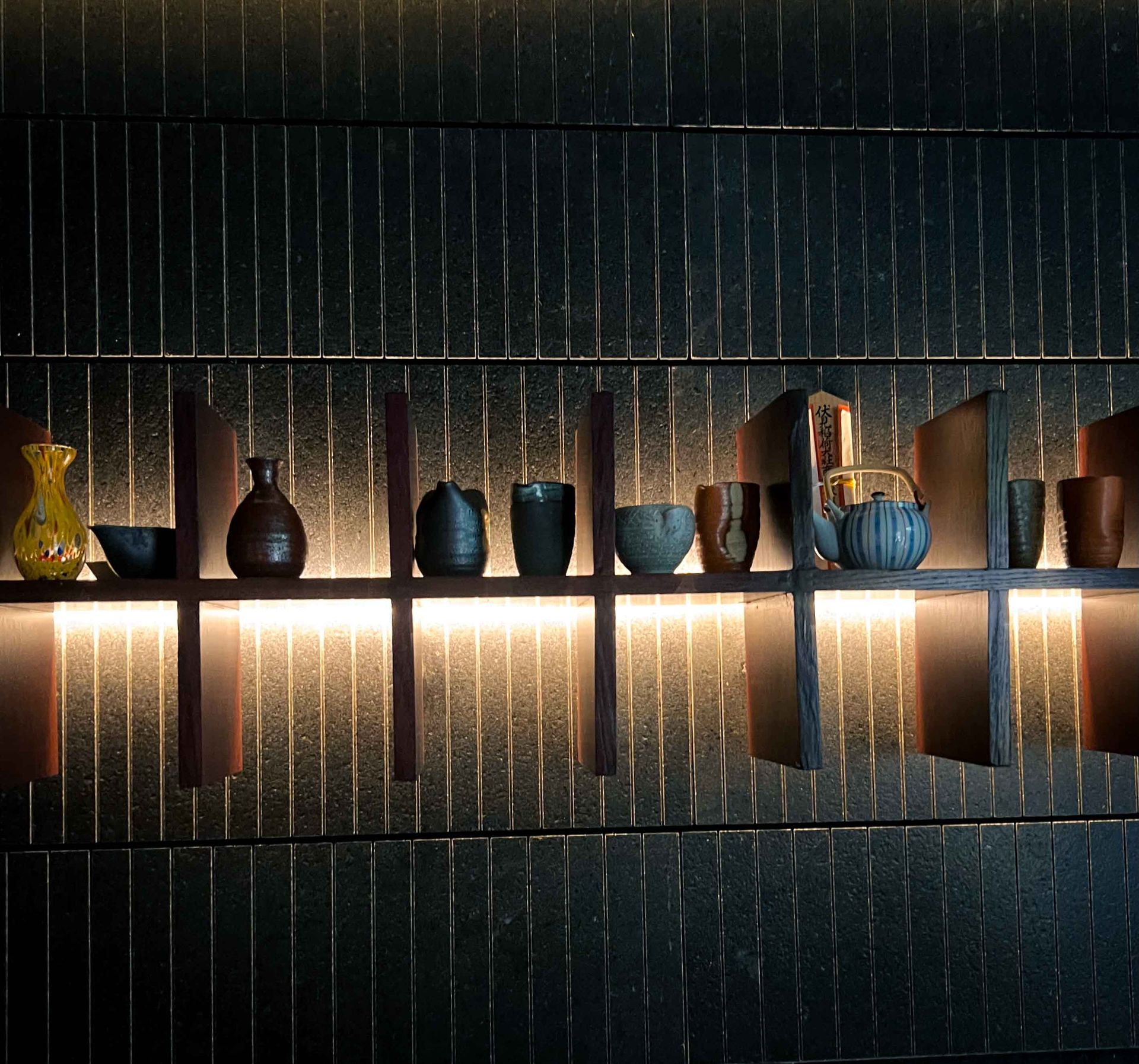 A shelf with a lot of vases and cups on it