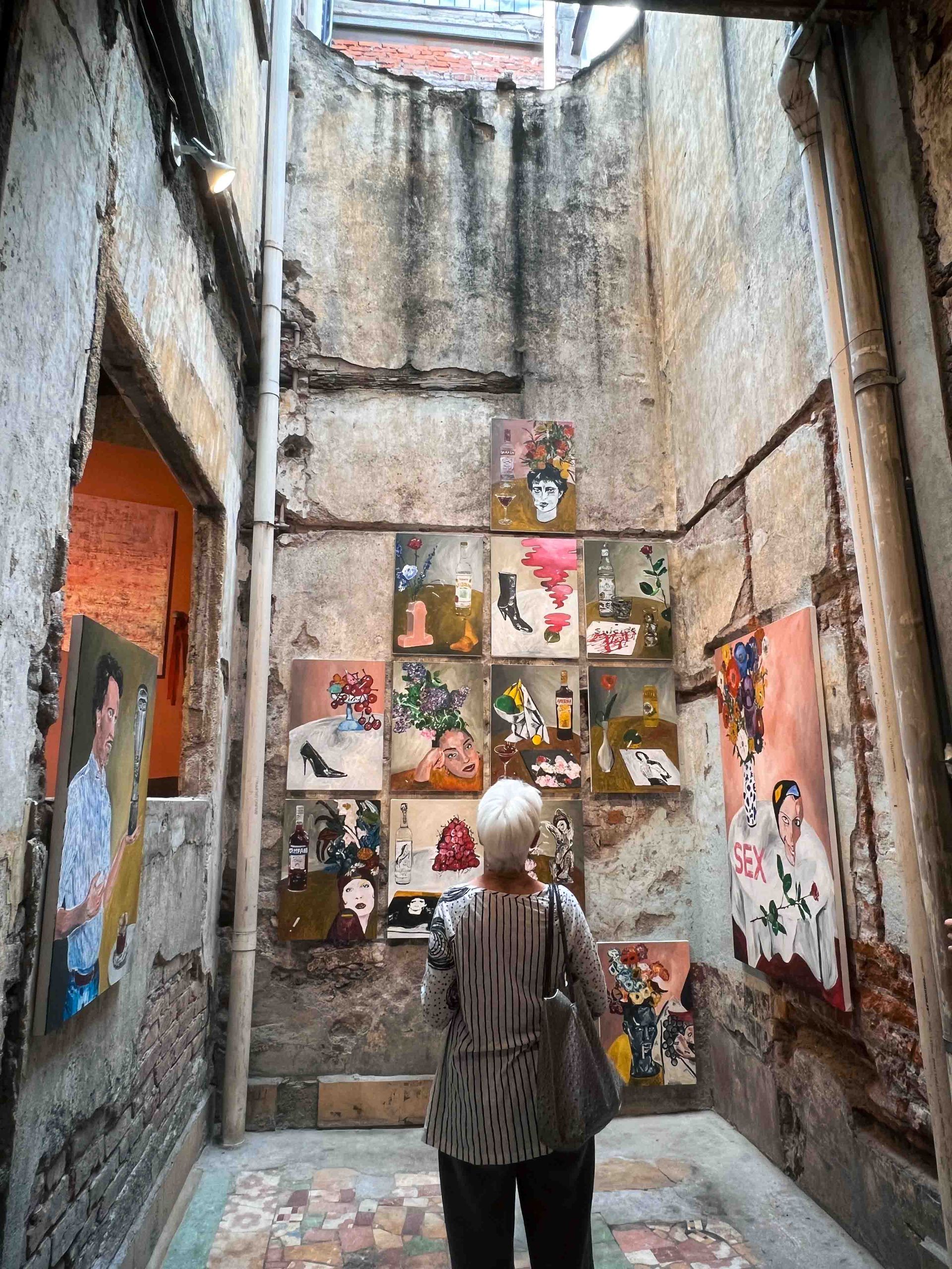 A woman is standing in a hallway with paintings on the wall.