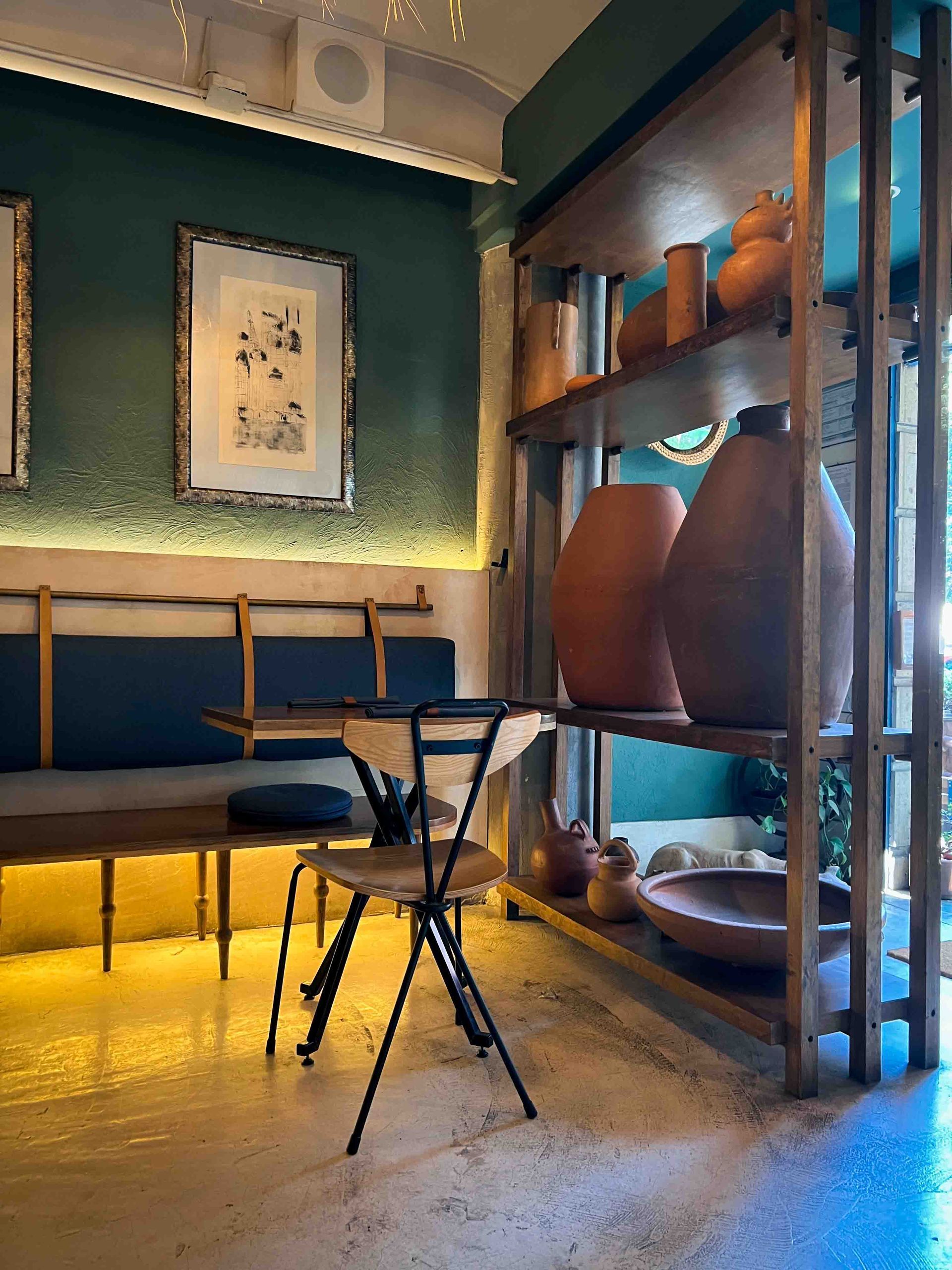 A room with a table and chairs and a shelf with vases on it