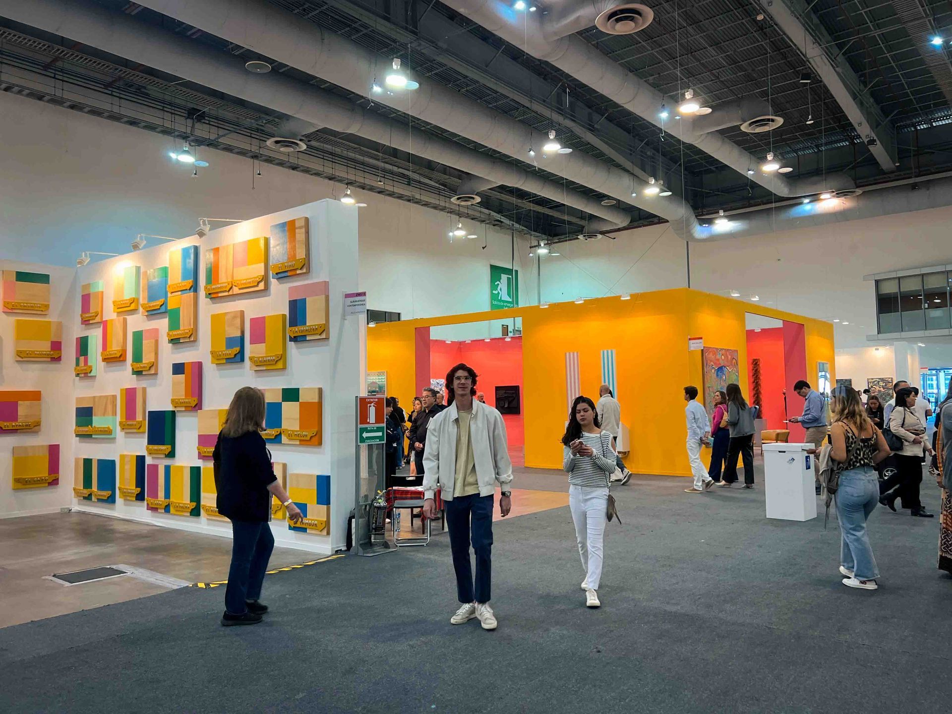 A group of people are standing in a room with paintings on the wall.