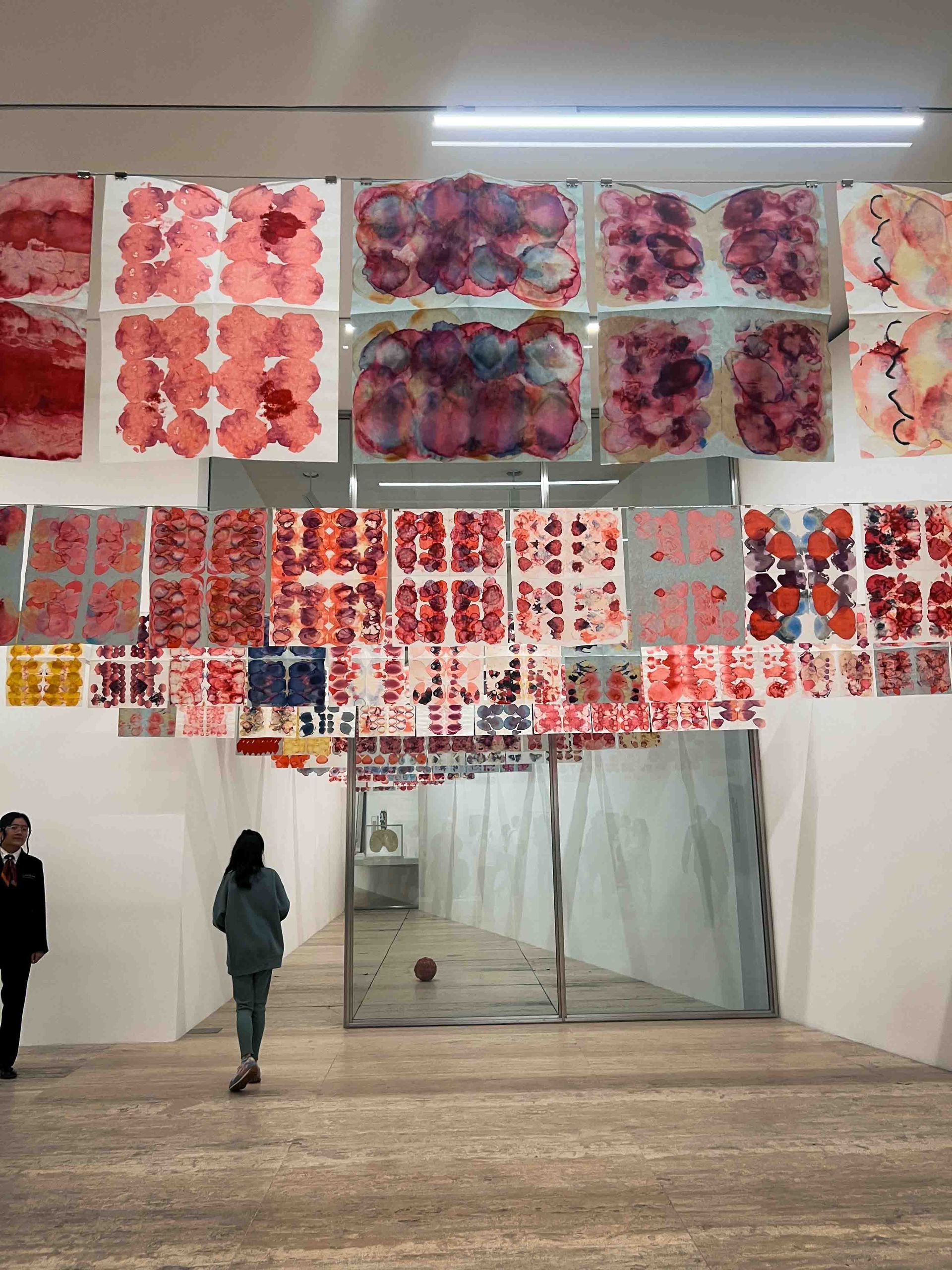 A woman is walking through a museum with a lot of paintings on the walls.
