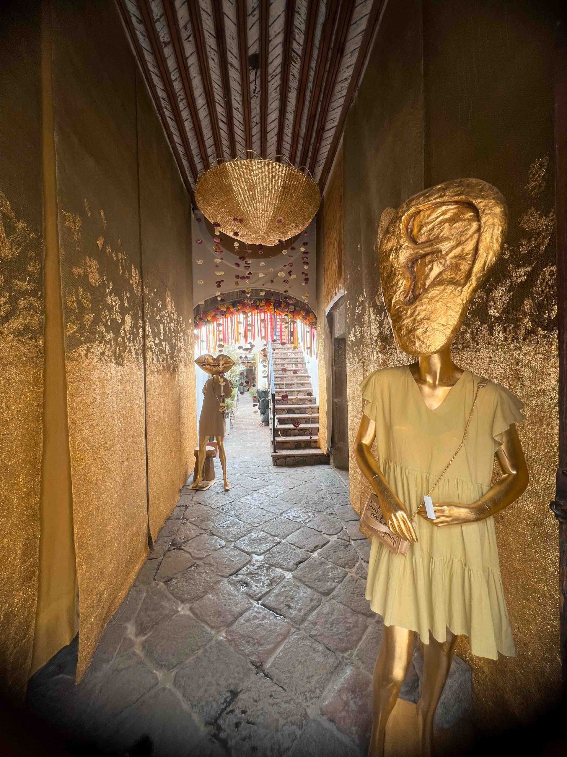 A statue of a woman in a yellow dress is standing in a hallway.