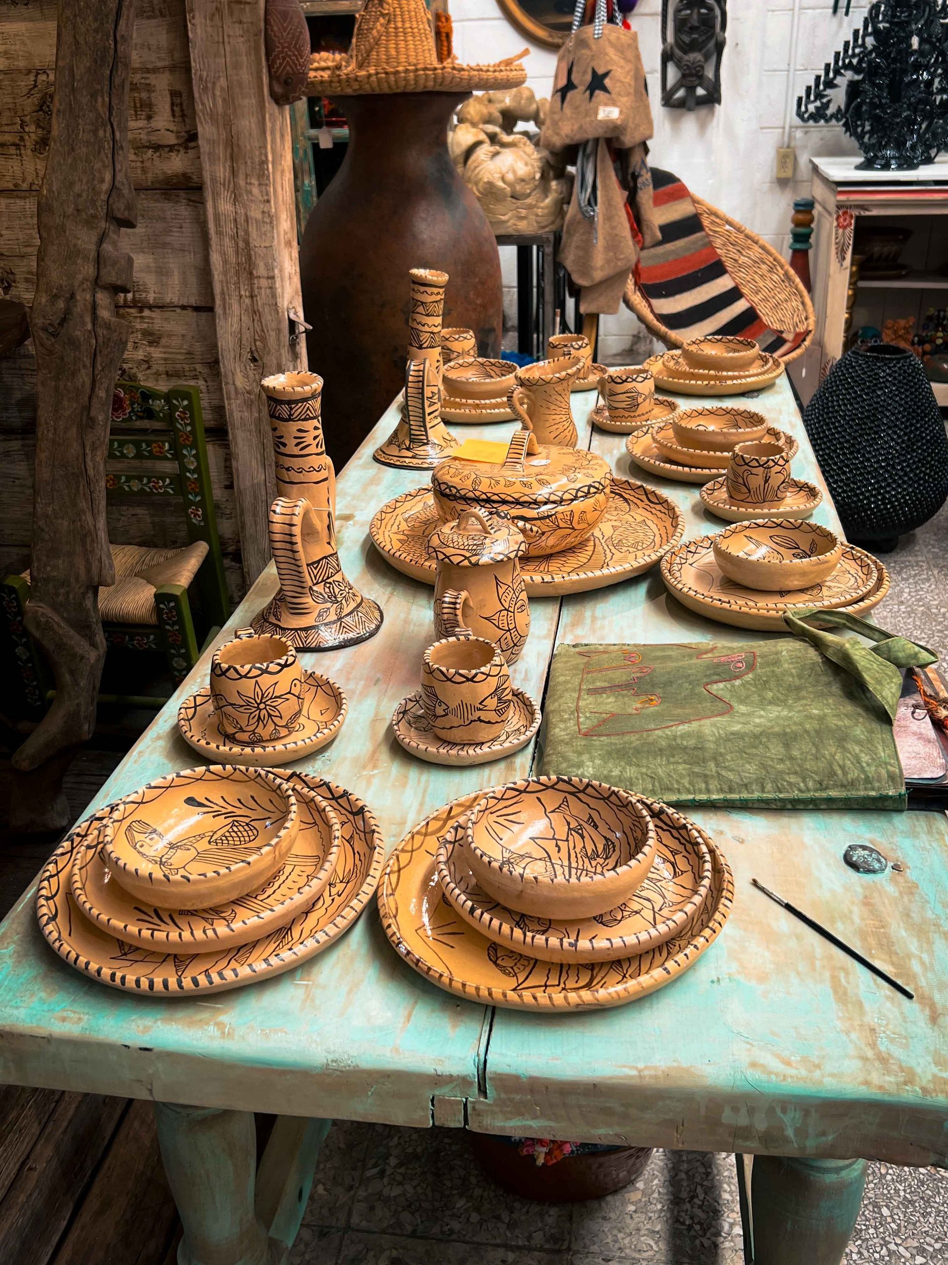 A table with plates , bowls , vases and candles on it.