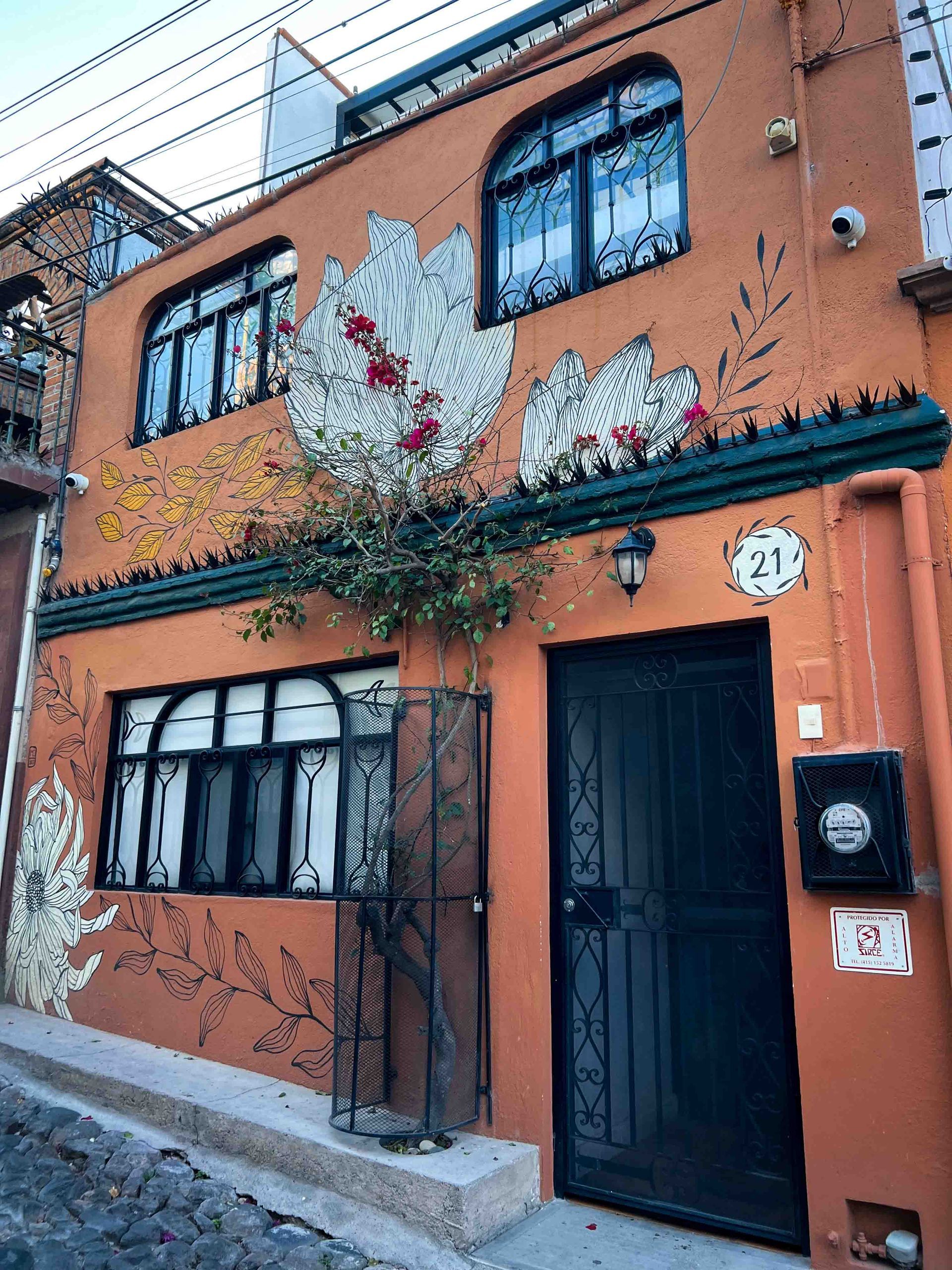 A building with a mural on the side of it and a black door.