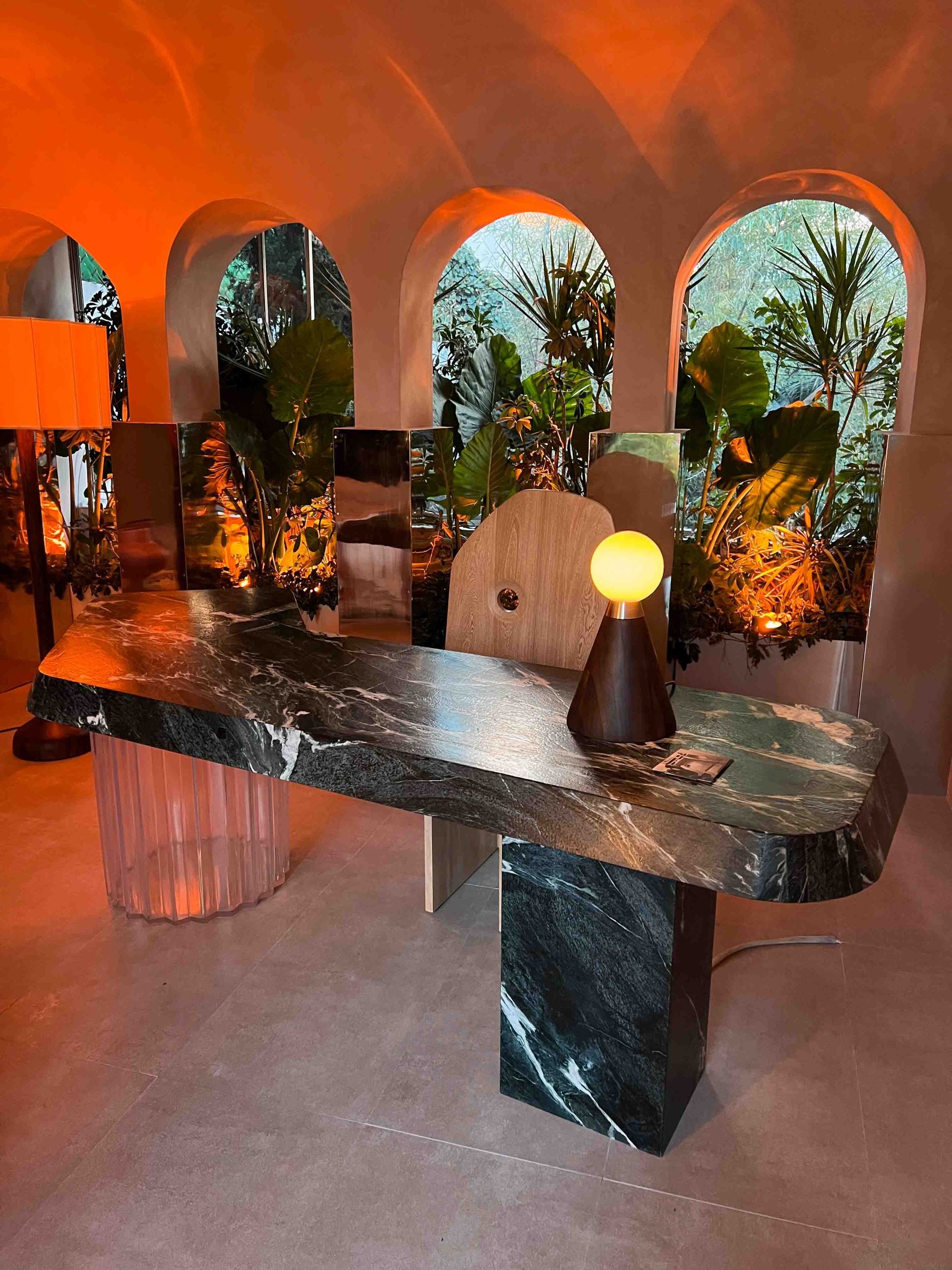 A marble table with a lamp on it in a room with arched windows.