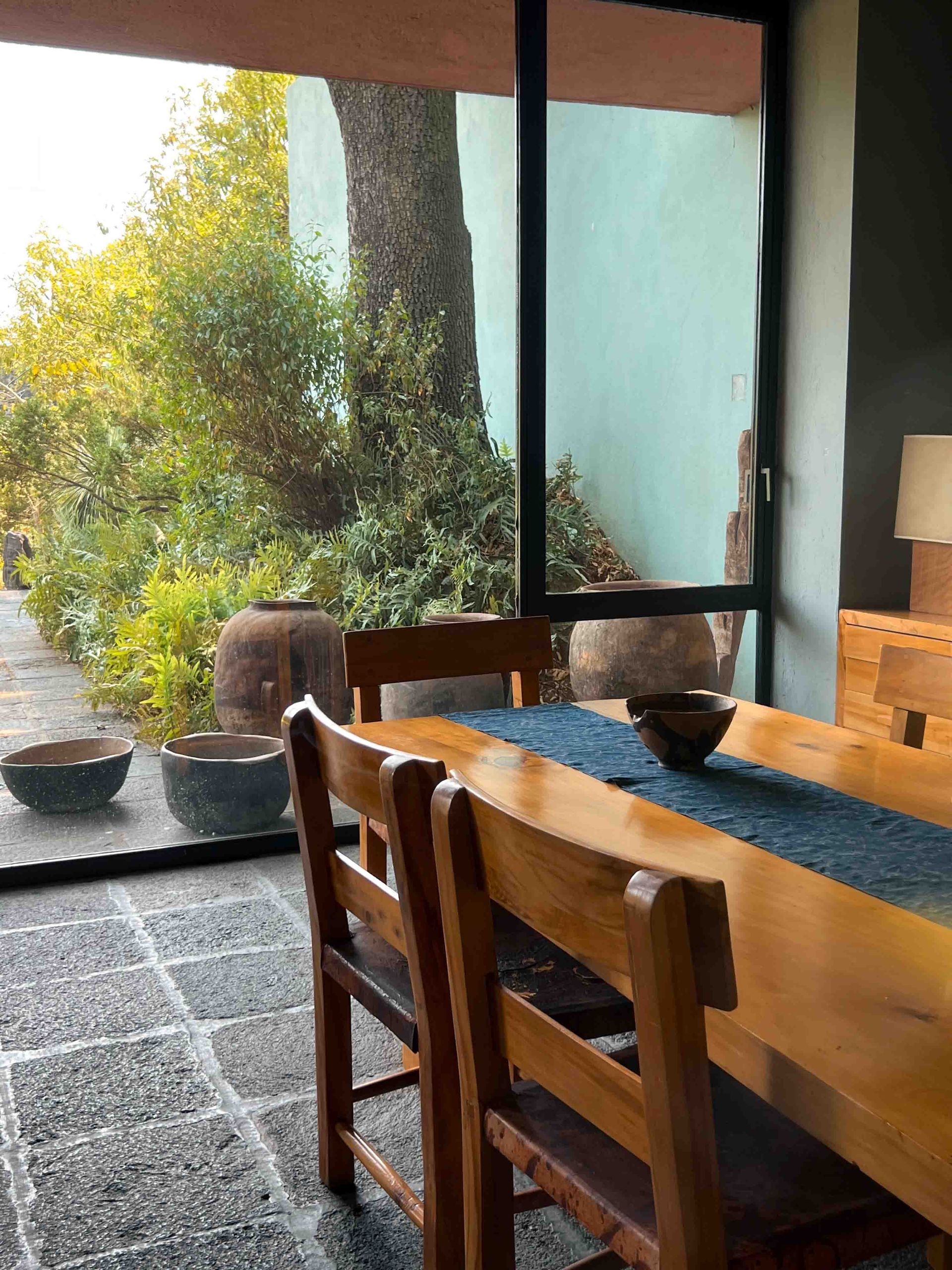 A wooden table and chairs in a dining room with a large window.
