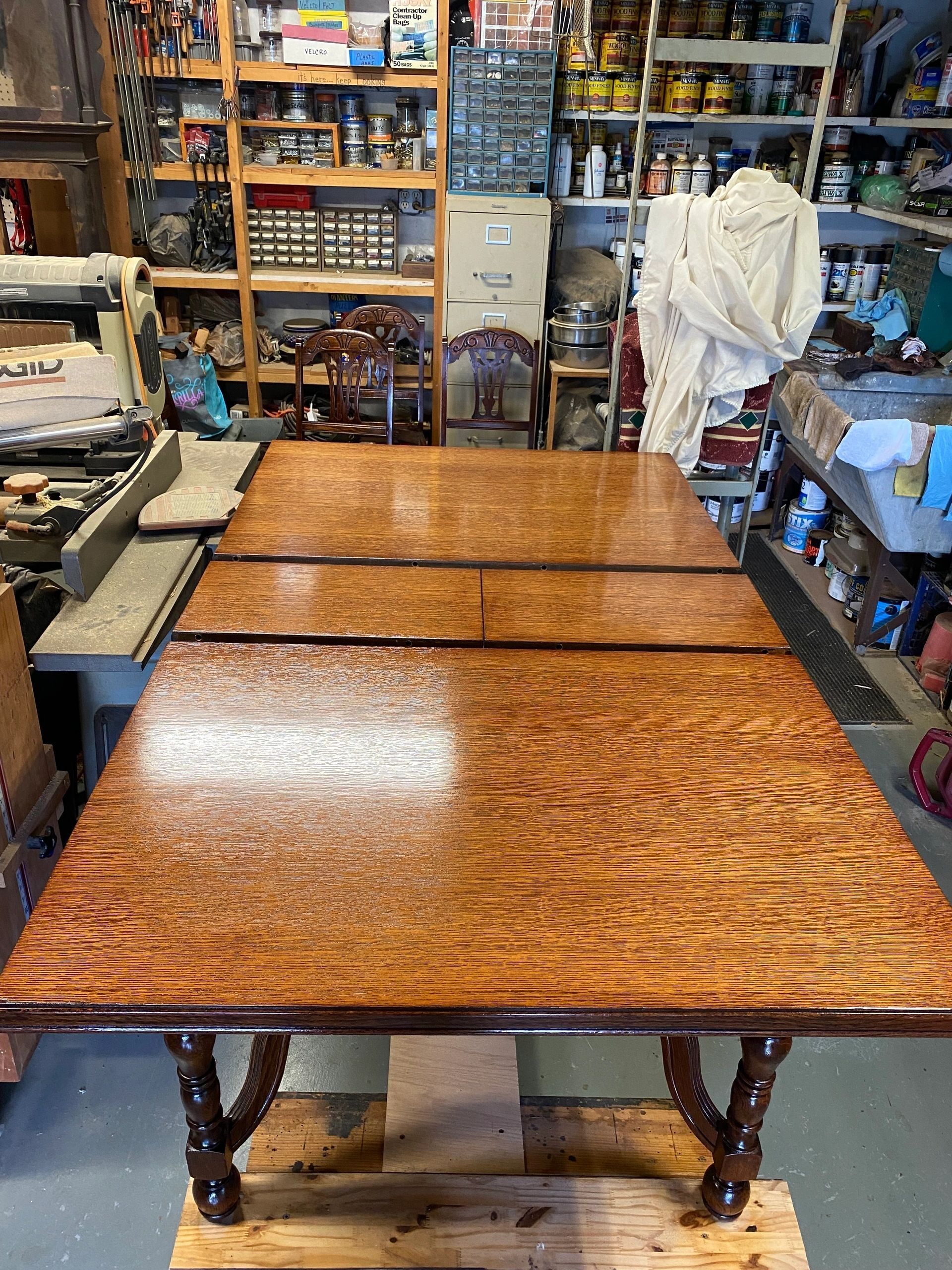 Refinished wooden dining table with ornate legs, in a workshop setting.