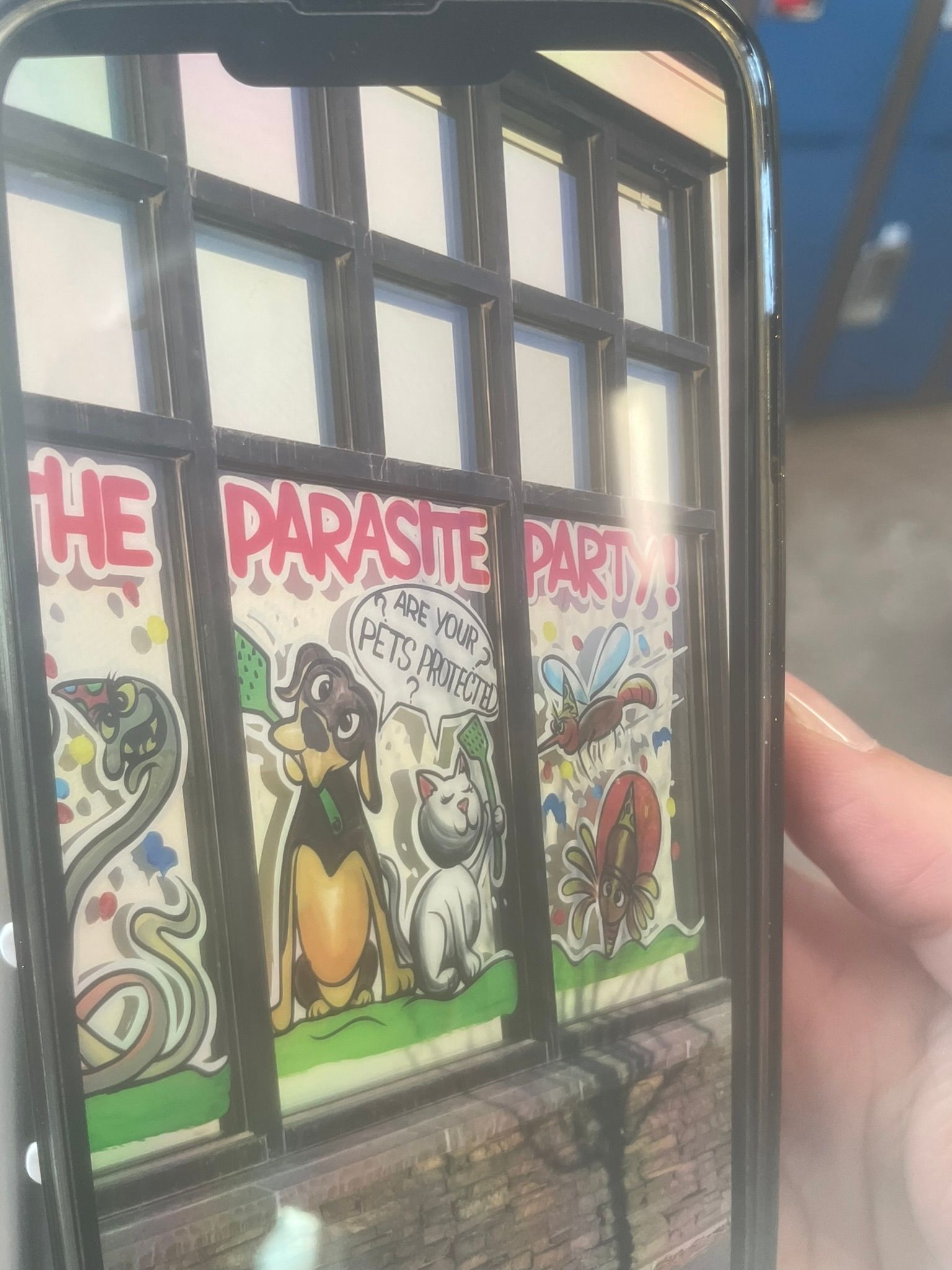 A person is holding a cell phone with a picture of a dog and cat on it.