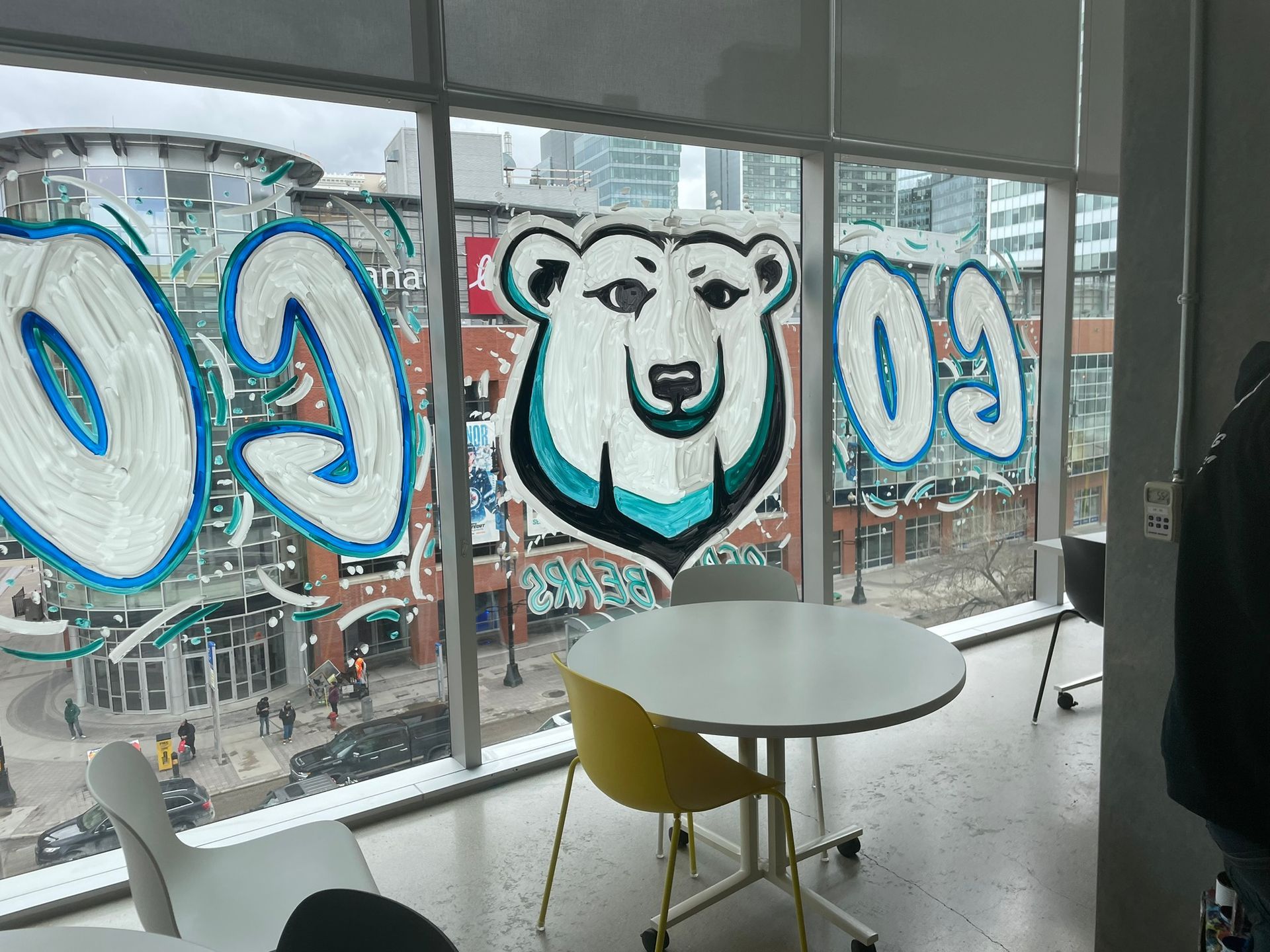 A room with a table and chairs and graffiti on the windows.