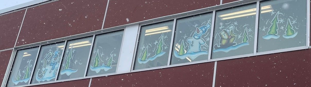 A row of windows on a building with snow falling on them.