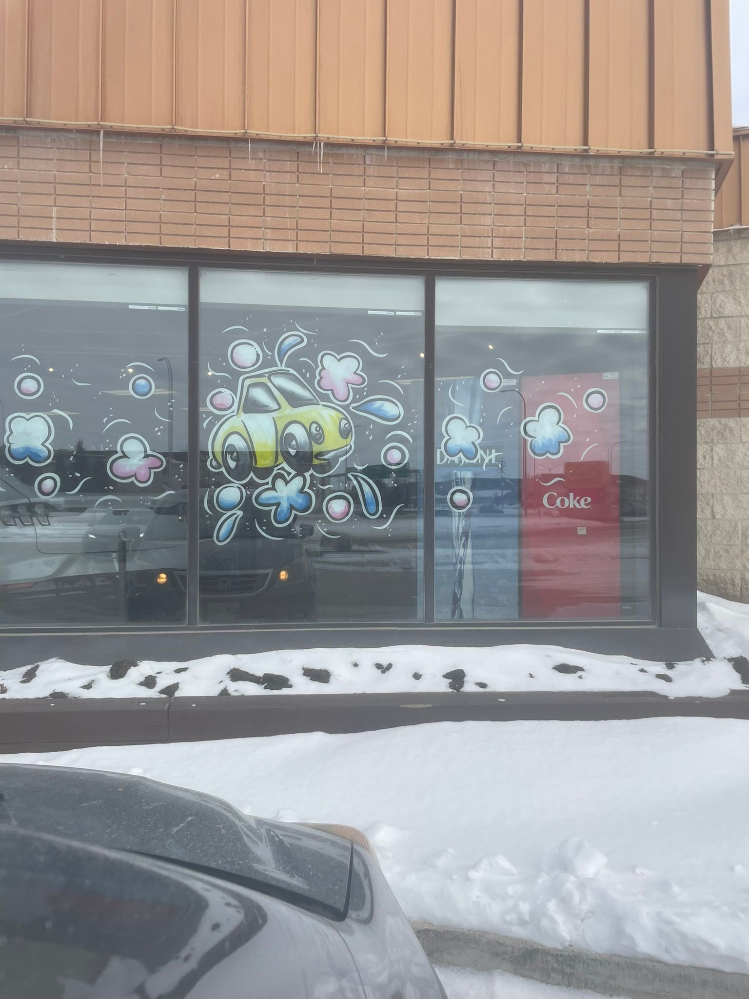 A car is parked in front of a building with snow on the ground.