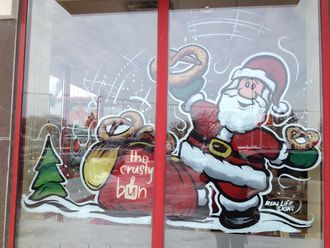 A drawing of santa claus on a window that says the crusty bun