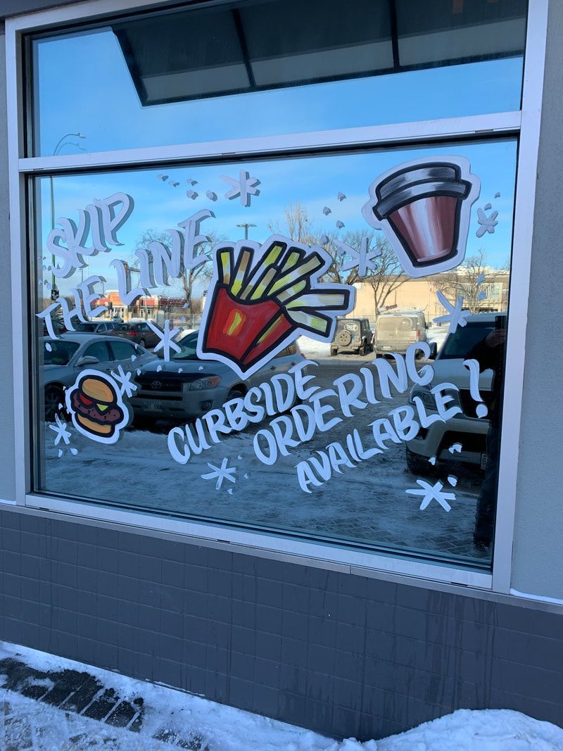 A window with a drawing of a hamburger , french fries , and a cup of coffee on it.