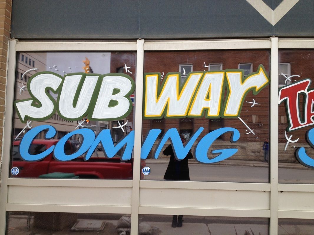 A window with subway coming written on it