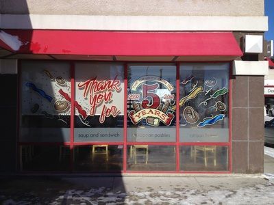 A restaurant with a red awning and a painting on the windows.