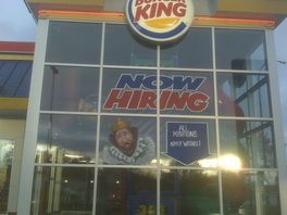 A burger king restaurant with a sign that says now hiring
