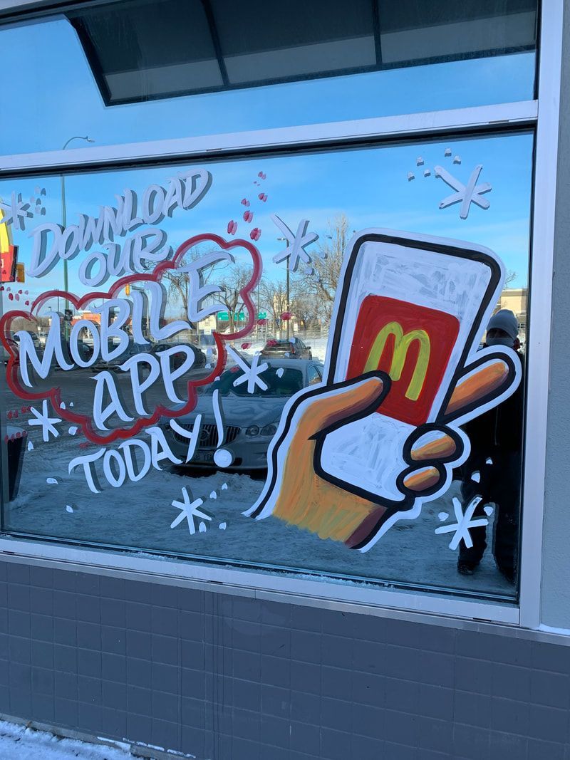 A mcdonald 's window has a drawing of a hand holding a mcdonald 's app