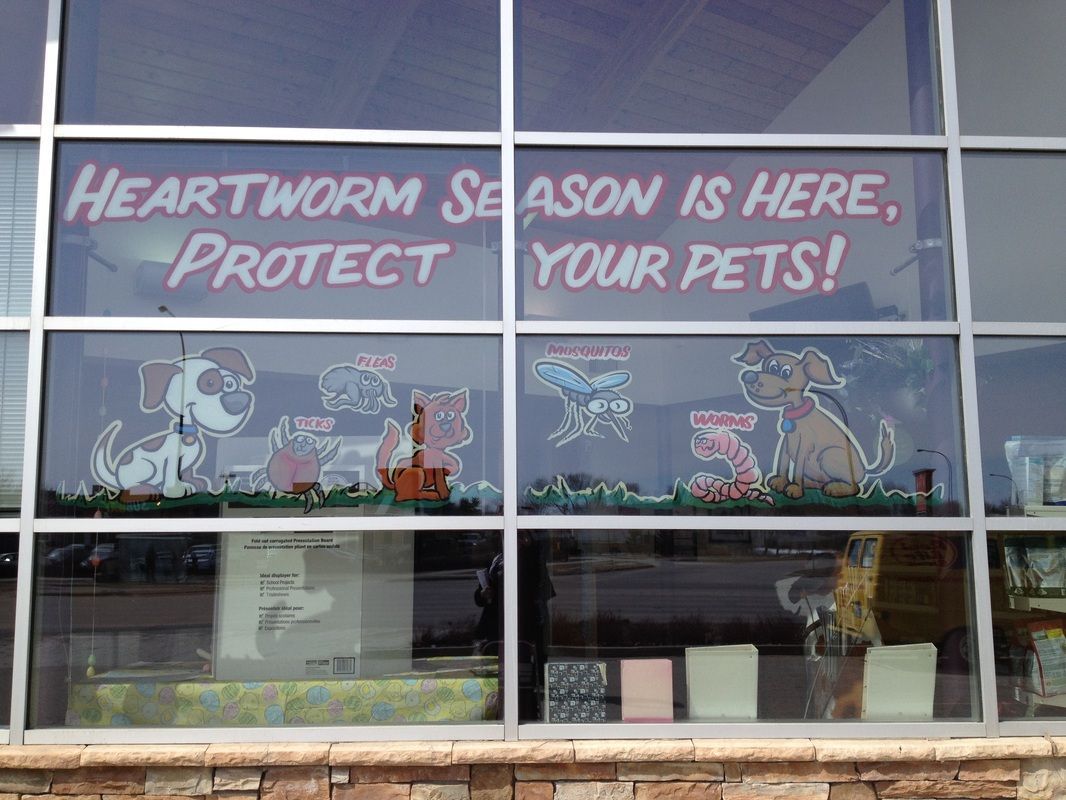 A window with a sign that says `` heartworm season is here , protect your pets ! ''