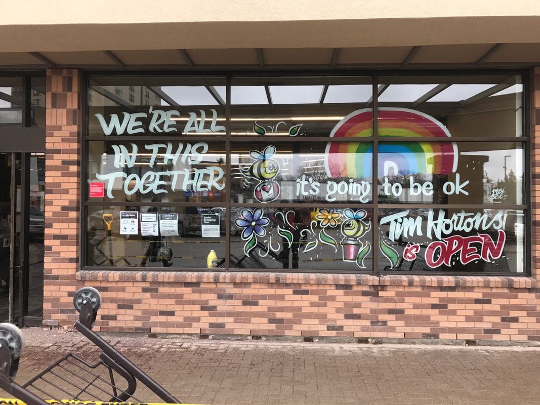 A store front with graffiti on the windows that says we 're all in this together