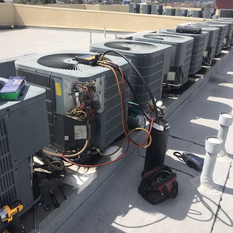Row of rooftop HVAC units with open panels, tools, and cables during maintenance