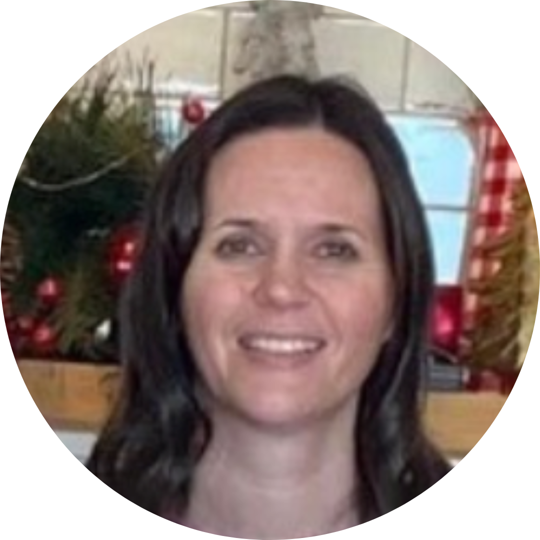A person with dark hair smiling at the camera, set against a blurred background featuring holiday decorations.